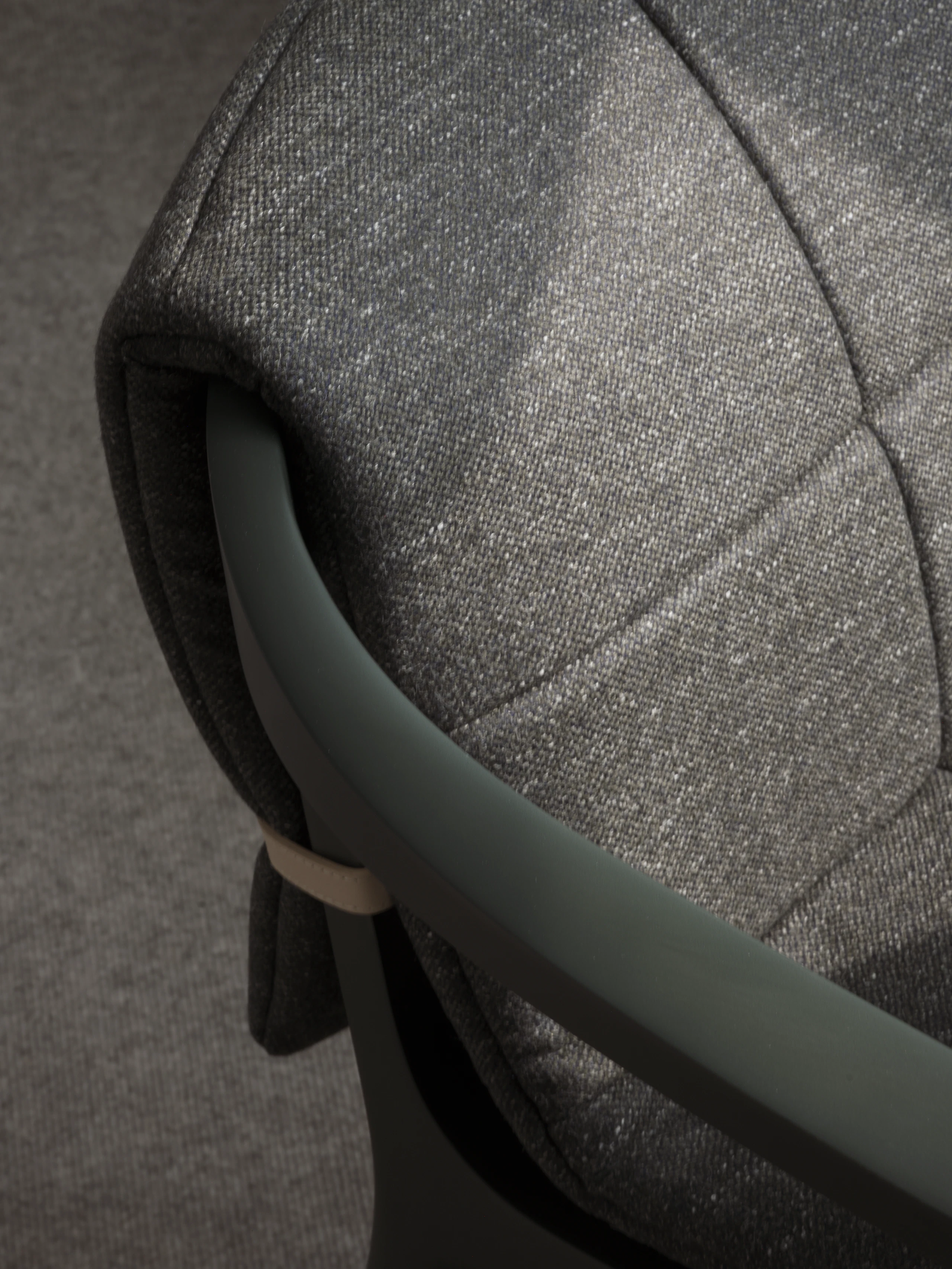 Detail view of a Lijn Armchair back and armrest in Ivy with a quilted wrap in Bellano Black Green, viewed from above at an angle.