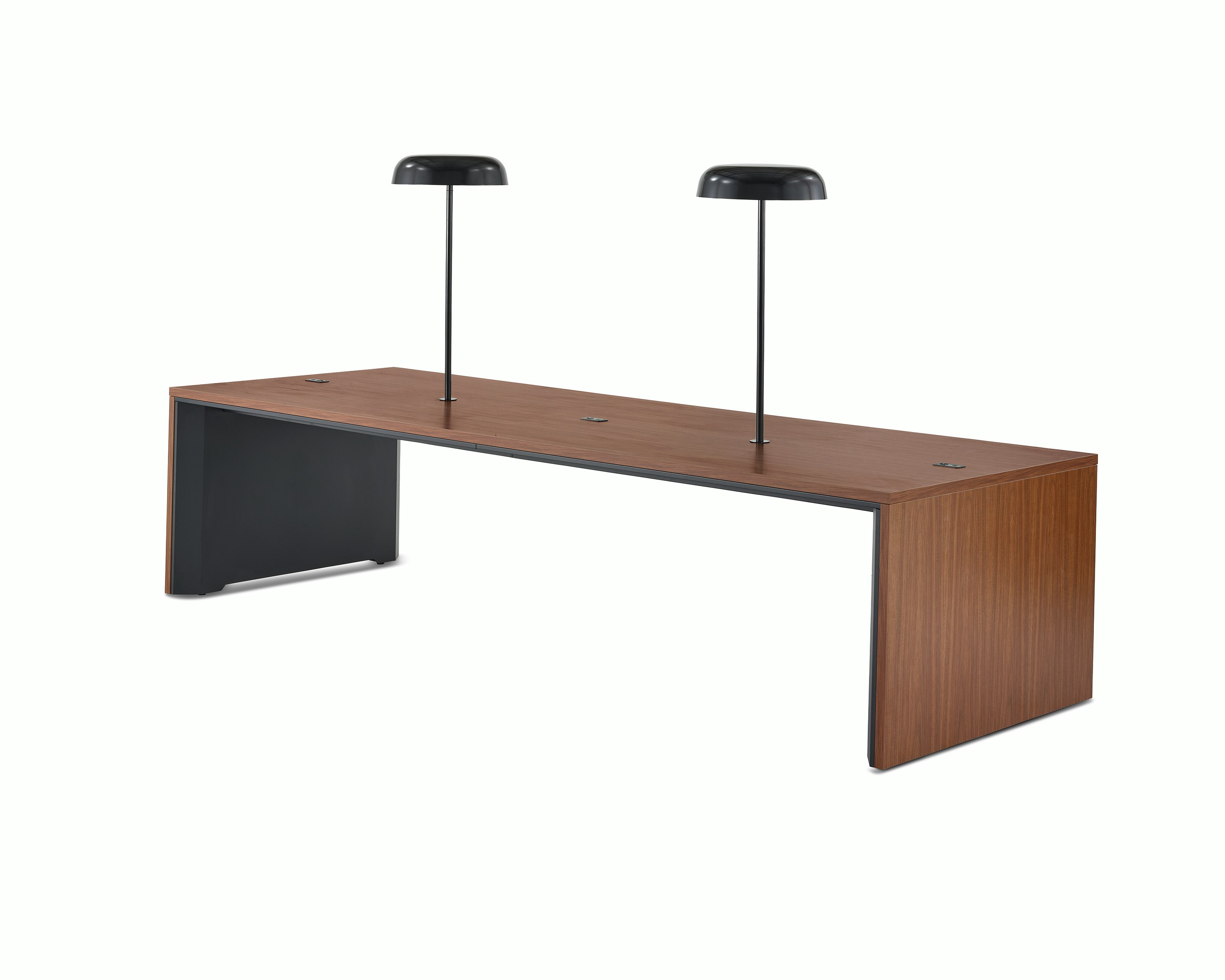 A wide communal Headway table at sitting height with a medium wood top with two black Ode lamps mounted on it, viewed at a 45-degree angle.