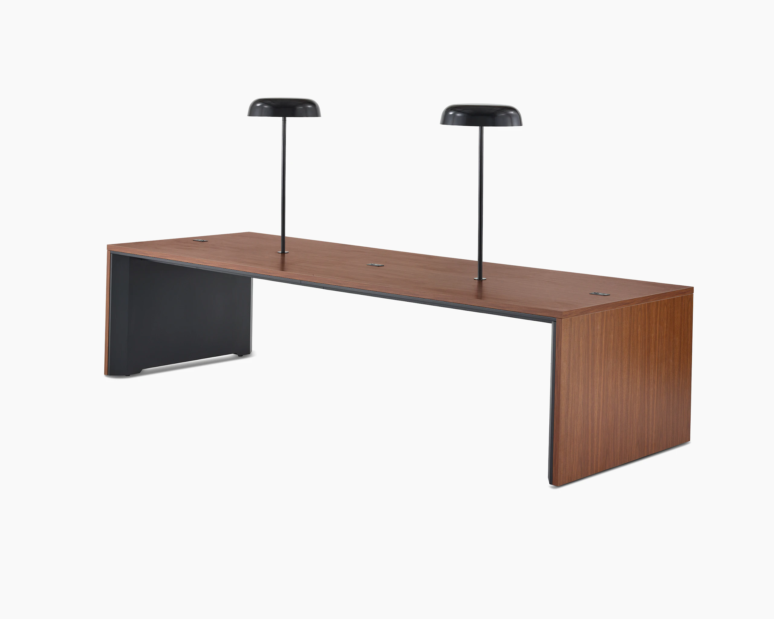 A wide communal Headway table at sitting height with a medium wood top with two black Ode lamps mounted on it, viewed at a 45-degree angle.