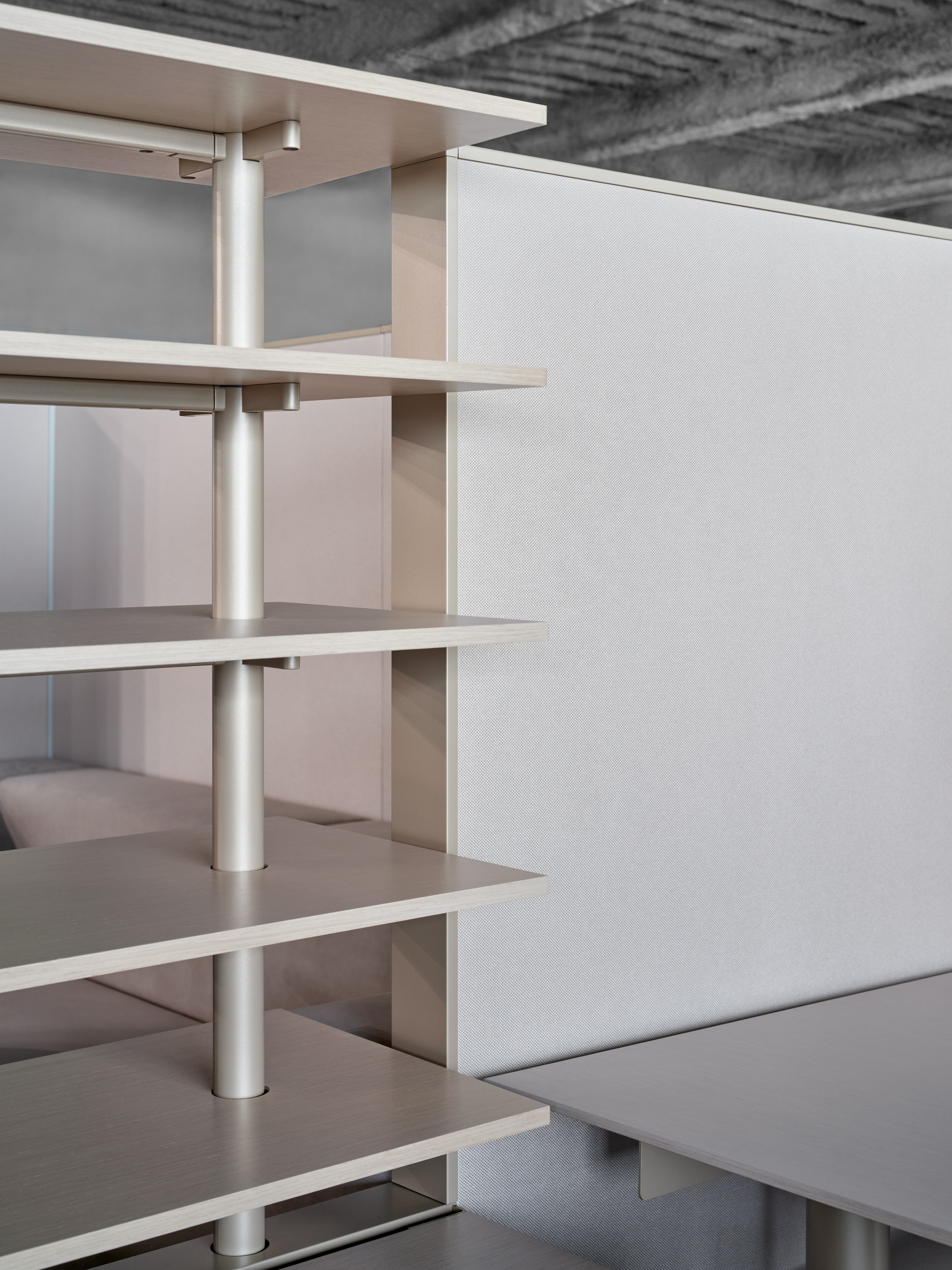 This is a detail style image of open shelves next to a height adjustable desk. The shelves are in line with the privacy panels of the workstation.