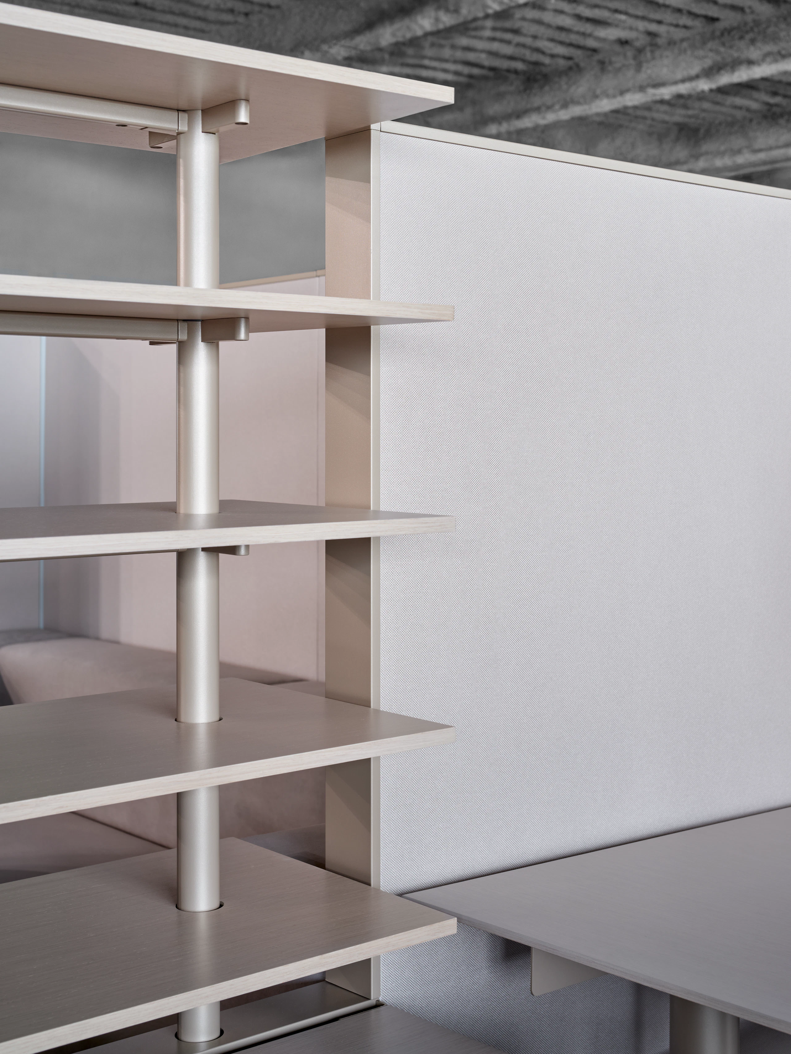 This is a detail style image of open shelves next to a height adjustable desk. The shelves are in line with the privacy panels of the workstation.