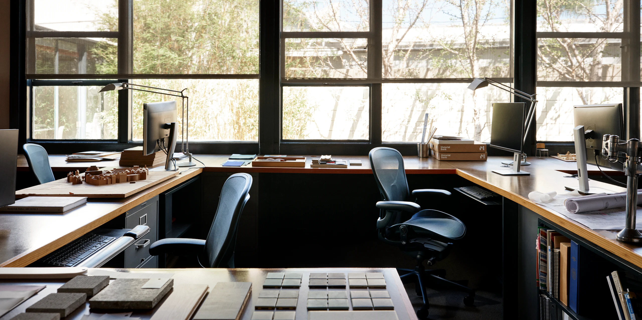 Two Aeron Chairs in dark blue surrounded by multiple desks in an office.