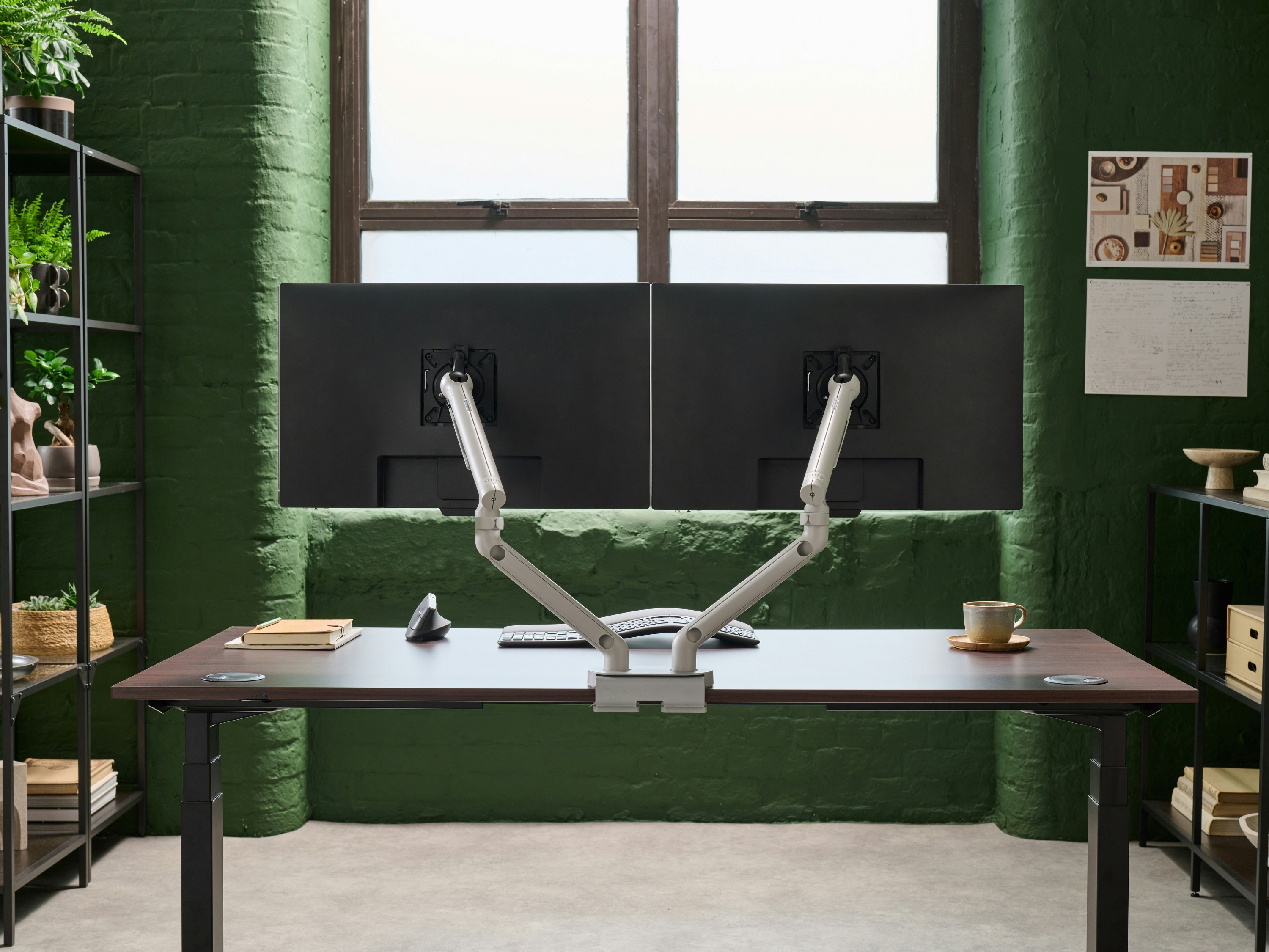 Desk with silver Flo Dual monitor arm in a working environment.