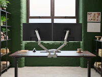 Desk with silver Flo Dual monitor arm in a working environment.