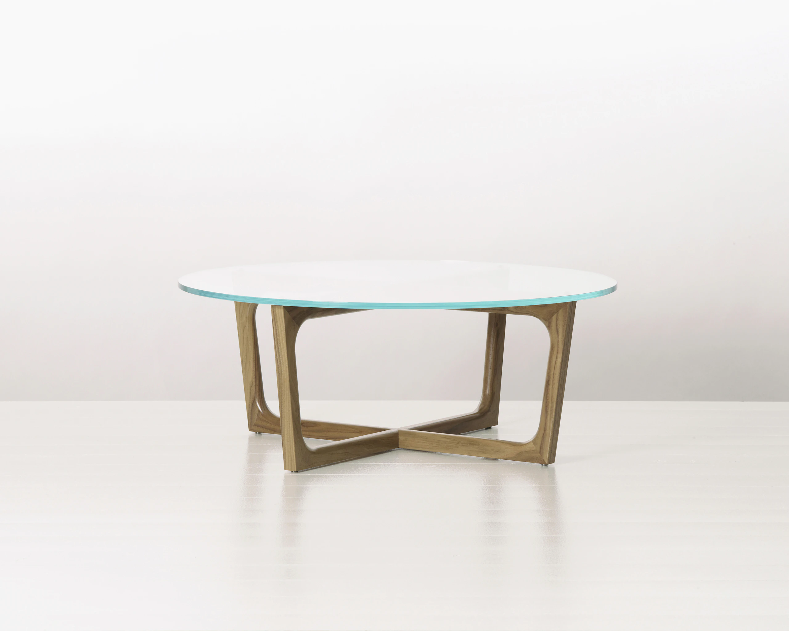 A round Loophole coffee table with a glass top and a walnut base.
