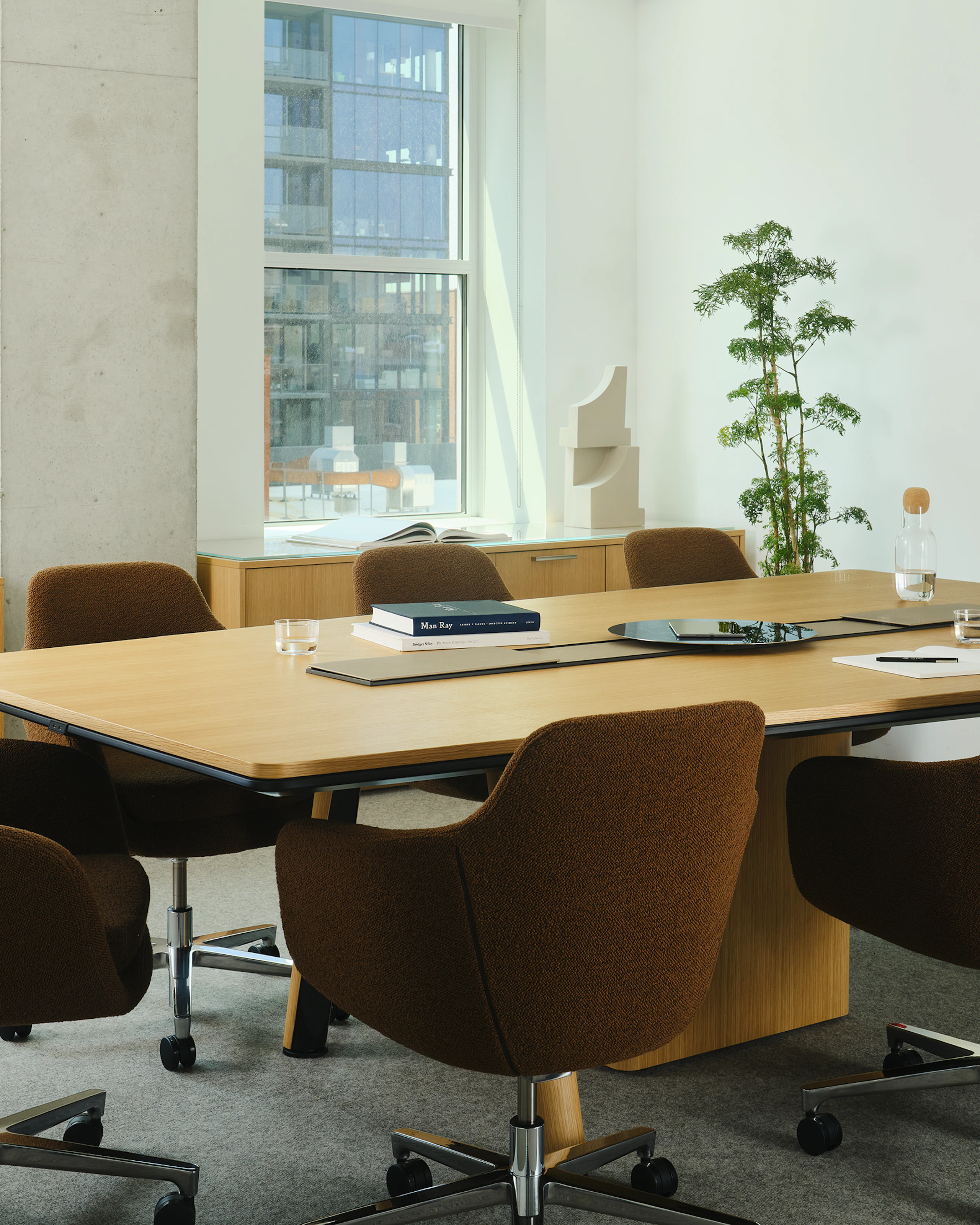 Ascent Conference Table designed by EOOS for DatesWeiser in Natural Rift Cut Oak with a trapezoid top shown at an angle surrounded by Geiger Saiba chairs and two JD Credenzas