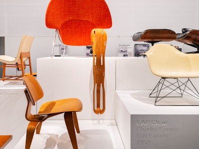 An LAR Chair, Eames Lounge Chair and Ottoman, Knoll Womb Chair, and others on white pedestals on display at the MillerKnoll Archives