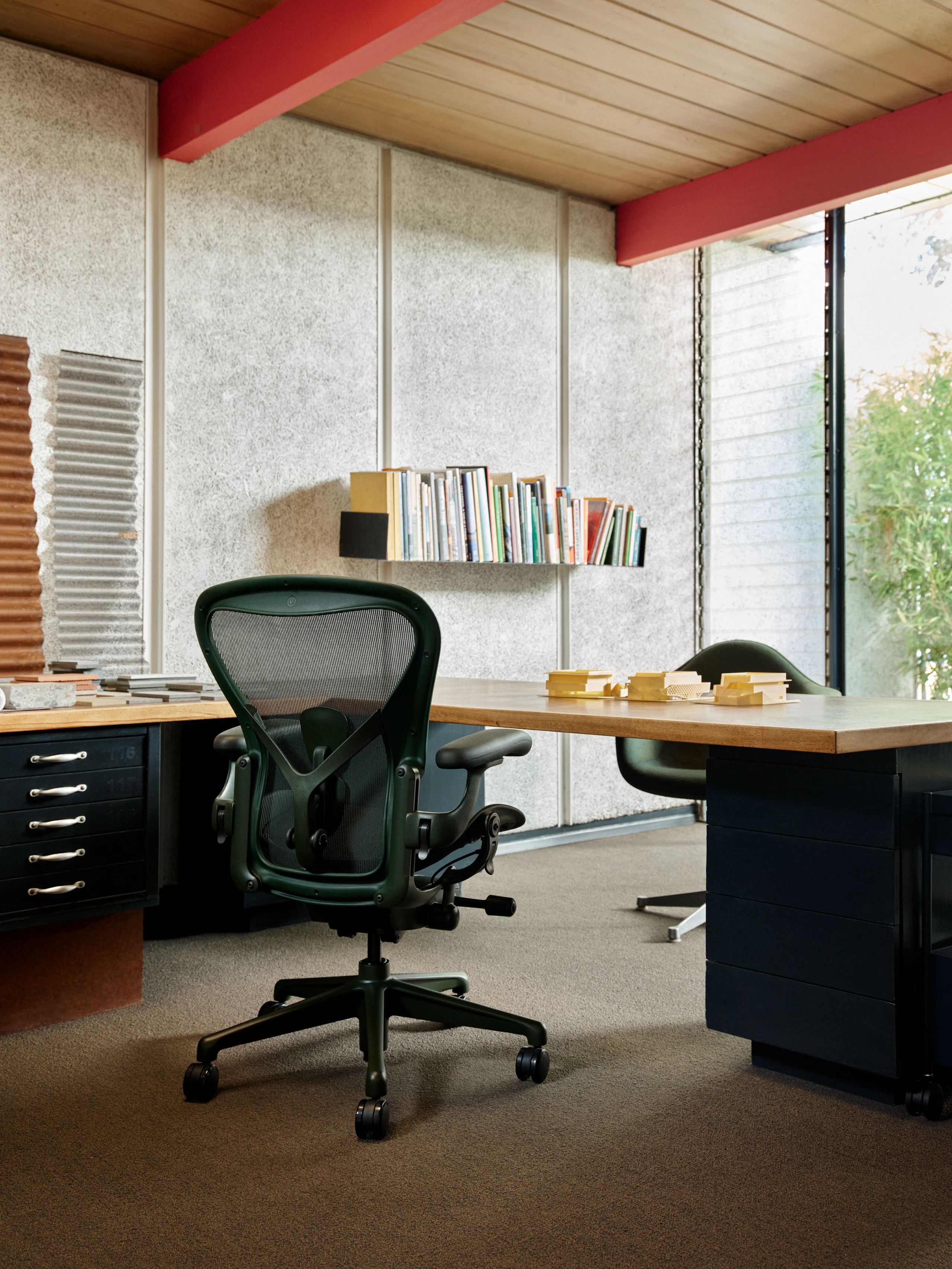 A dark green Aeron Chair at a custom desk in an office.
