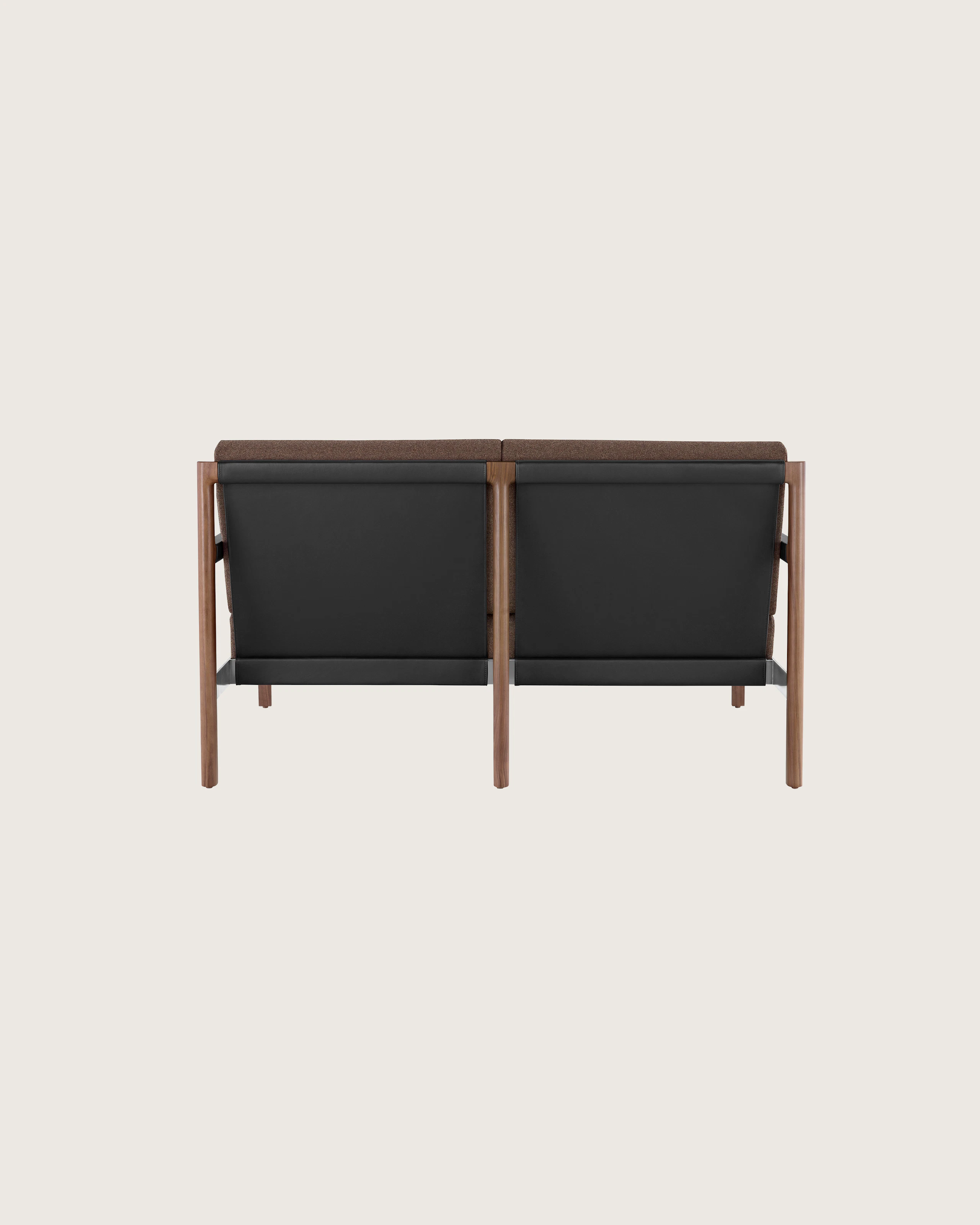 A Brabo Settee with dark upholstery, leather and metal accents, and an exposed wood frame. Viewed from the back.