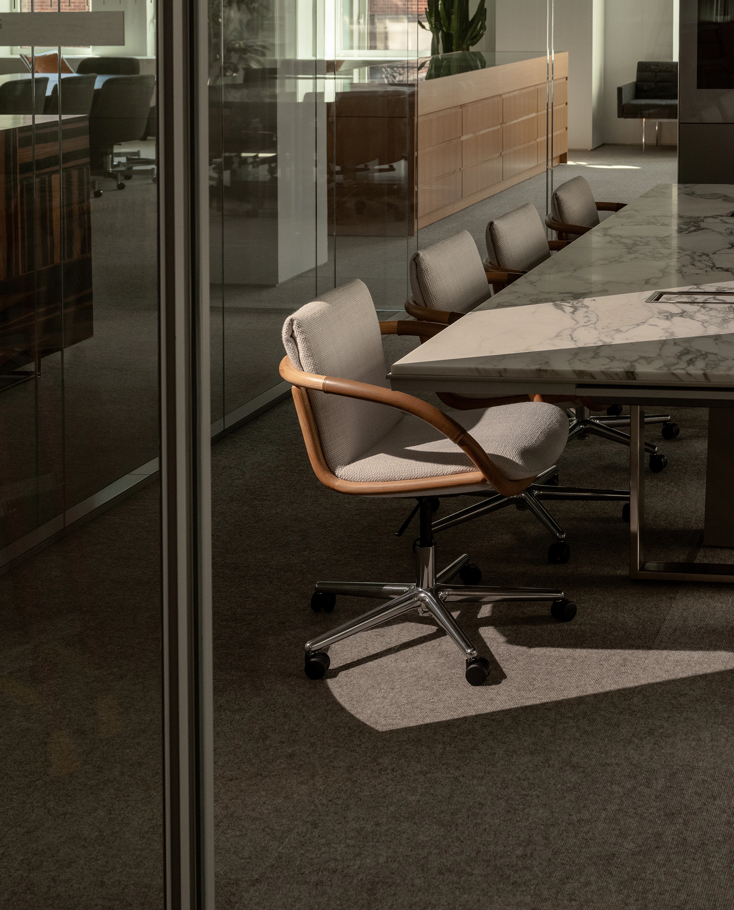 Four Full Loop Chairs designed by EOOS with an Oak frame upholstered with Capri in Snow, with a Highline Conference Table with an Arabescato Corchia marble top, at an angle.