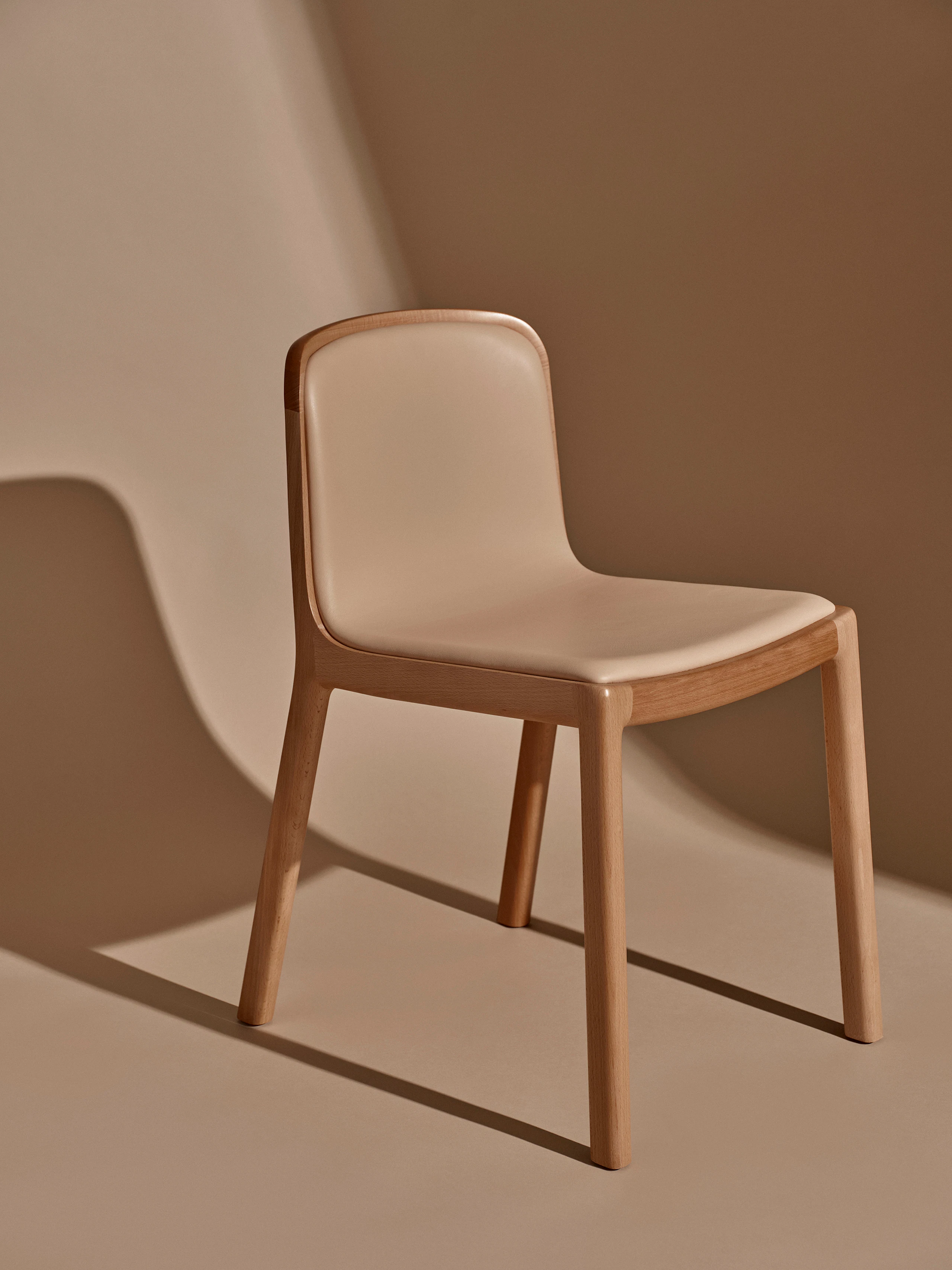 Lijn Side Chair designed by Carole Baijings in Oak, fully upholstered with Bristol Leather in Champagne, shown at an angle against a neutral studio background.