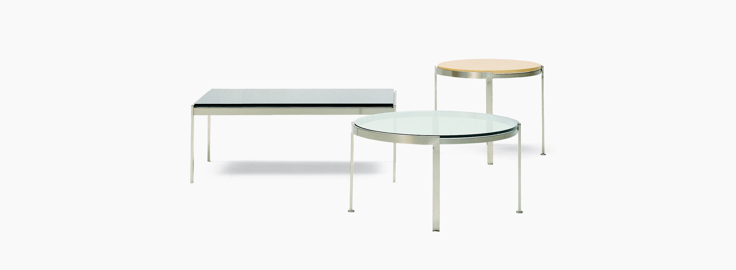 A round Metal Series side table with a wood top in the background and a round Metal Series coffee table in the foreground.