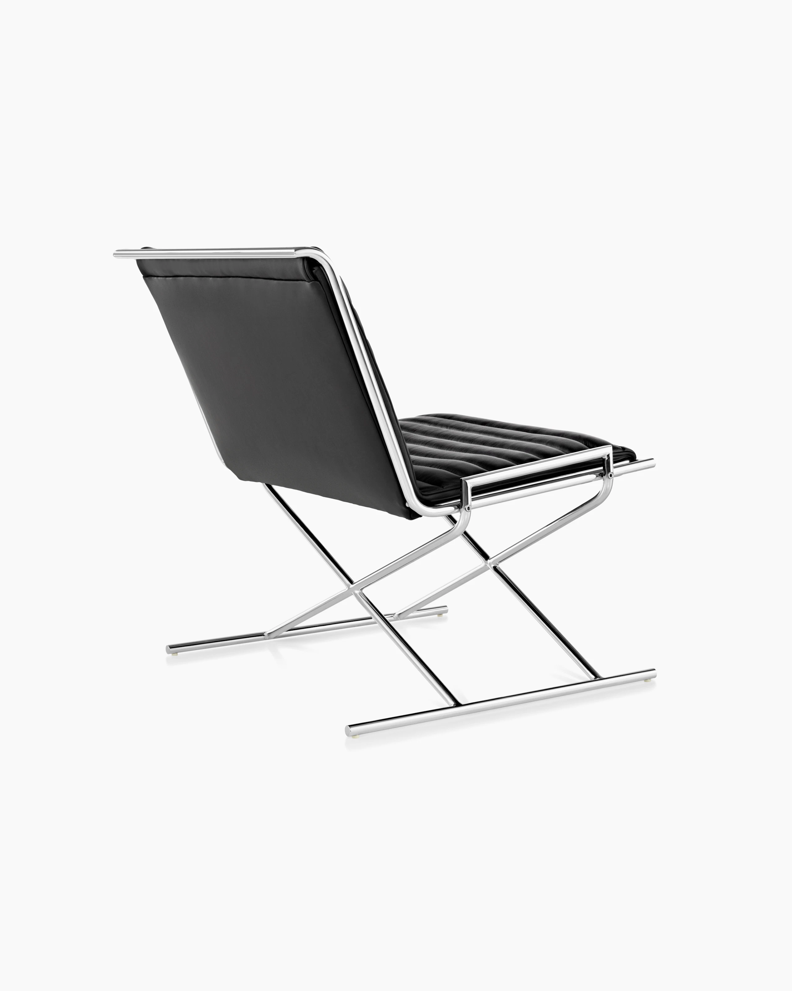 A Sled lounge chair with ribbed black leather upholstery and an X-shaped steel frame, viewed from behind at an angle.