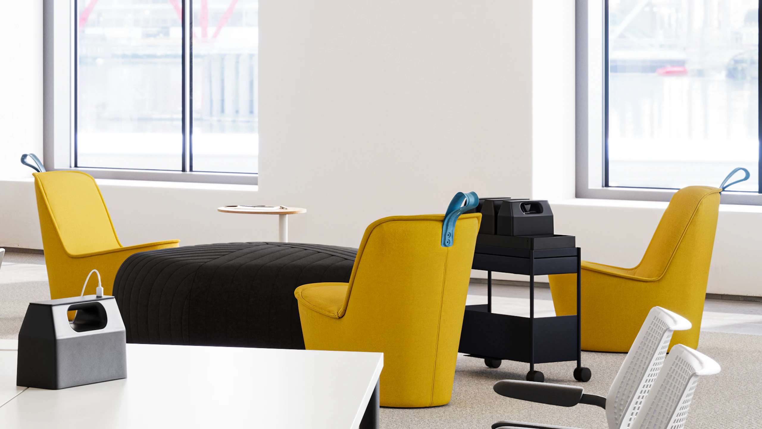 A communal seating area - furnished with yellow NaughtOne Pippin chairs and a Herman Miller OE1 Storage Trolley - used to encourage face-to-face interaction