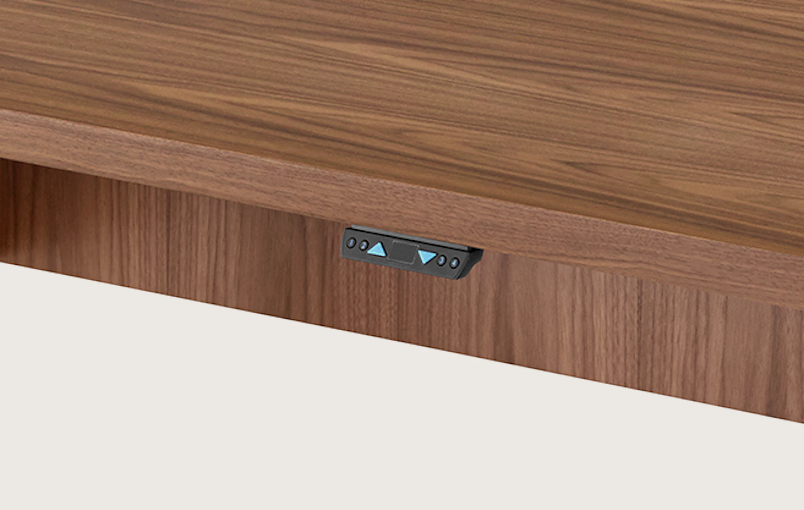A rectangular MP Height-Adjustable Table in the seated position, viewed from an angle and showing the height-adjustment button beneath the tabletop.