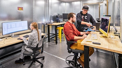 Three students working at computers on sit-to-stand tables