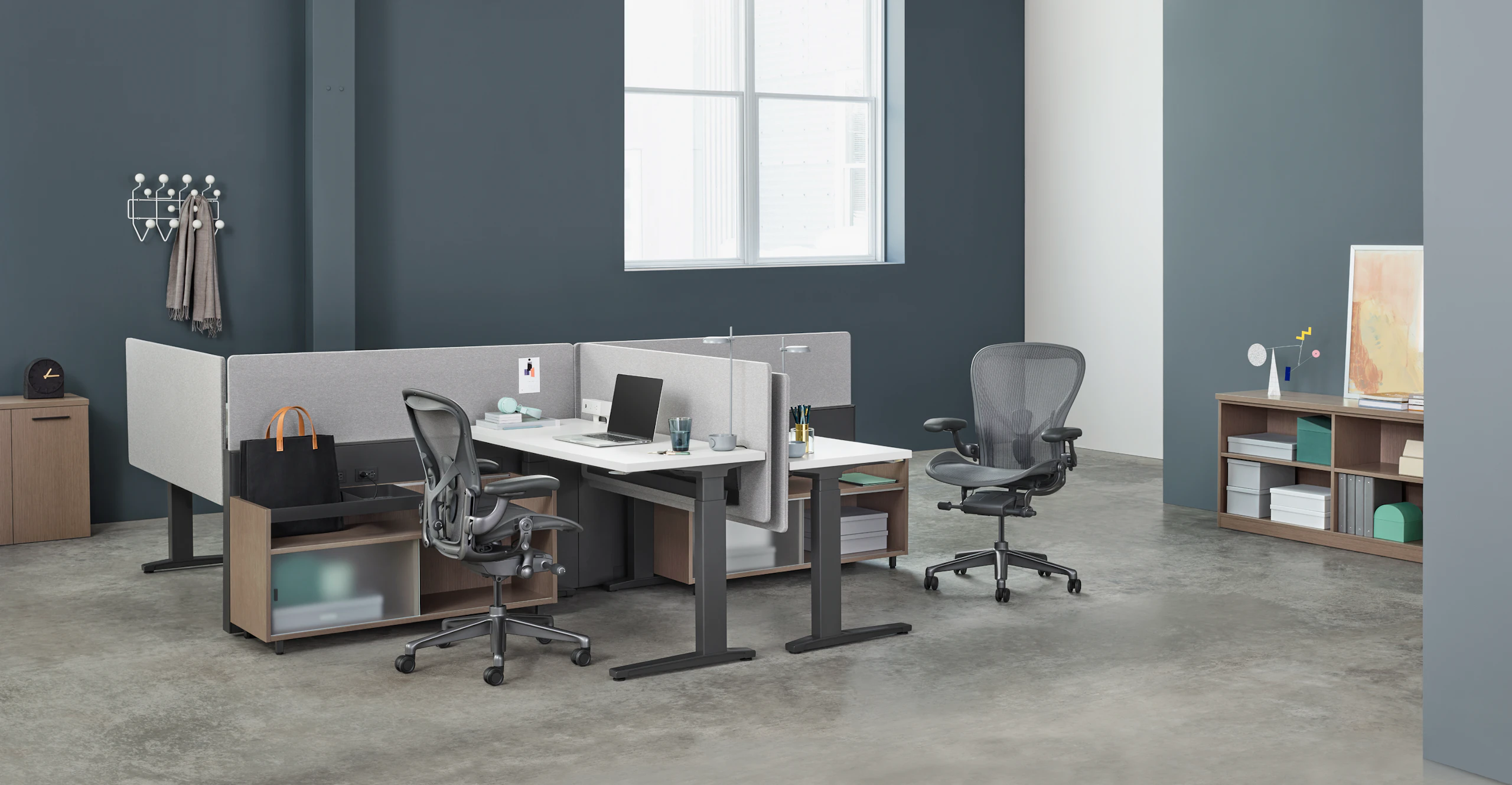 A four-person Canvas Channel workstation with lower storage, Renew Sit-to-Stand Tables, gray fabric screens, and dark gray Aeron Chairs