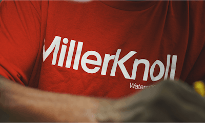 A person wearing a red MillerKnoll Watercarrier t-shirt.