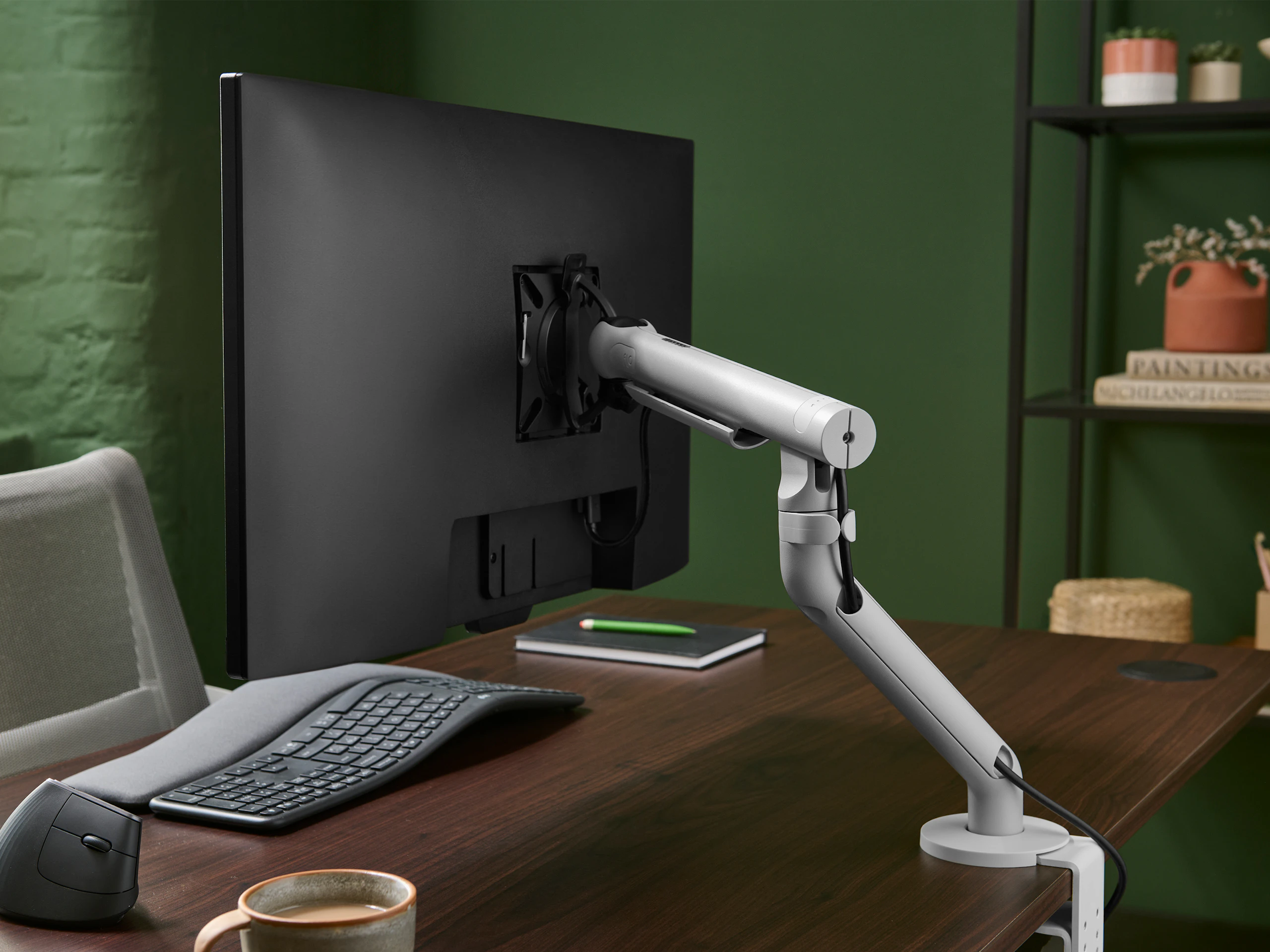 Silver Flo monitor arm viewed from the side in an office set up.