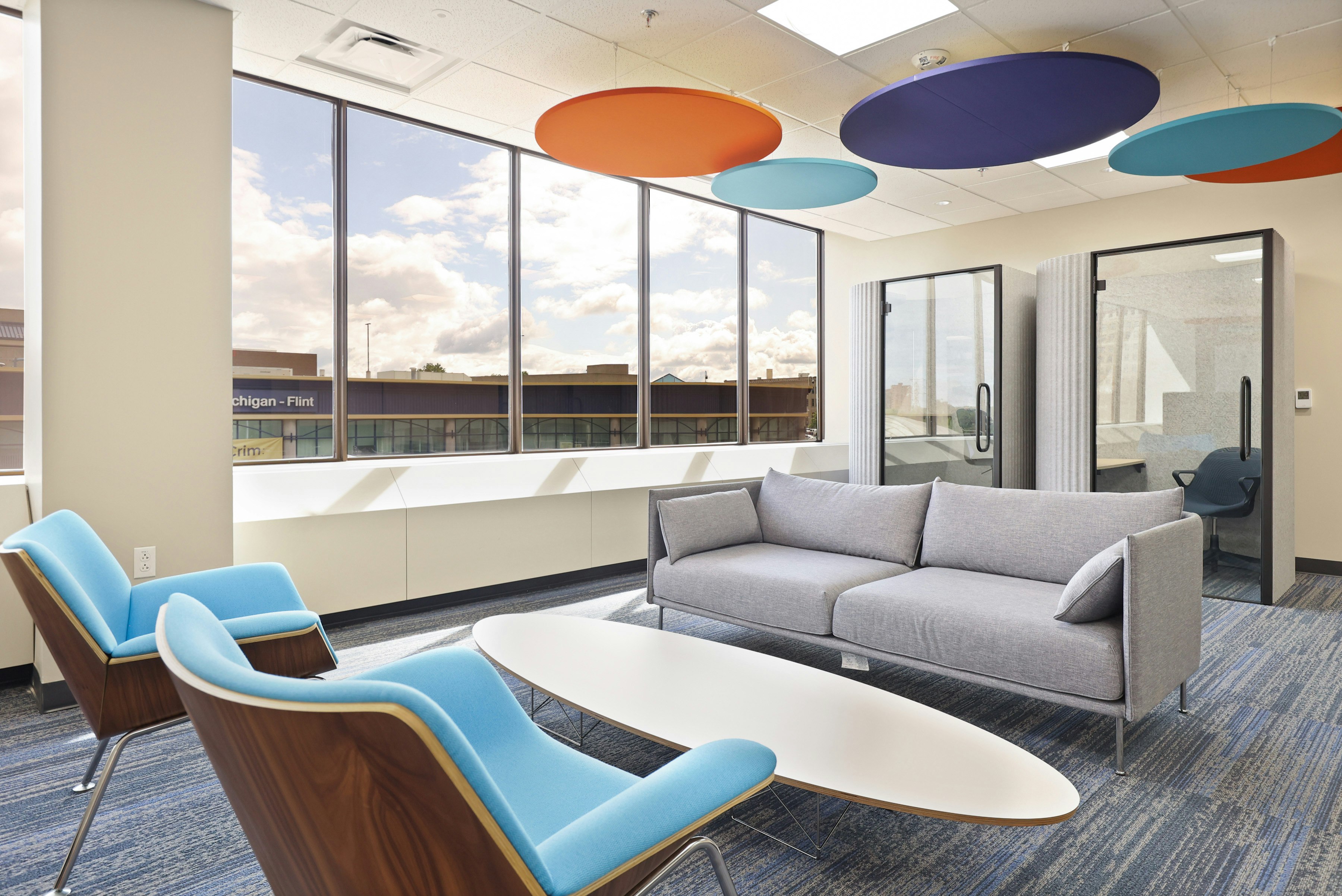 A group seating area at the Genesee County administration building furnished with a grey sofa, oval coffee table, and light blue lounge chair.