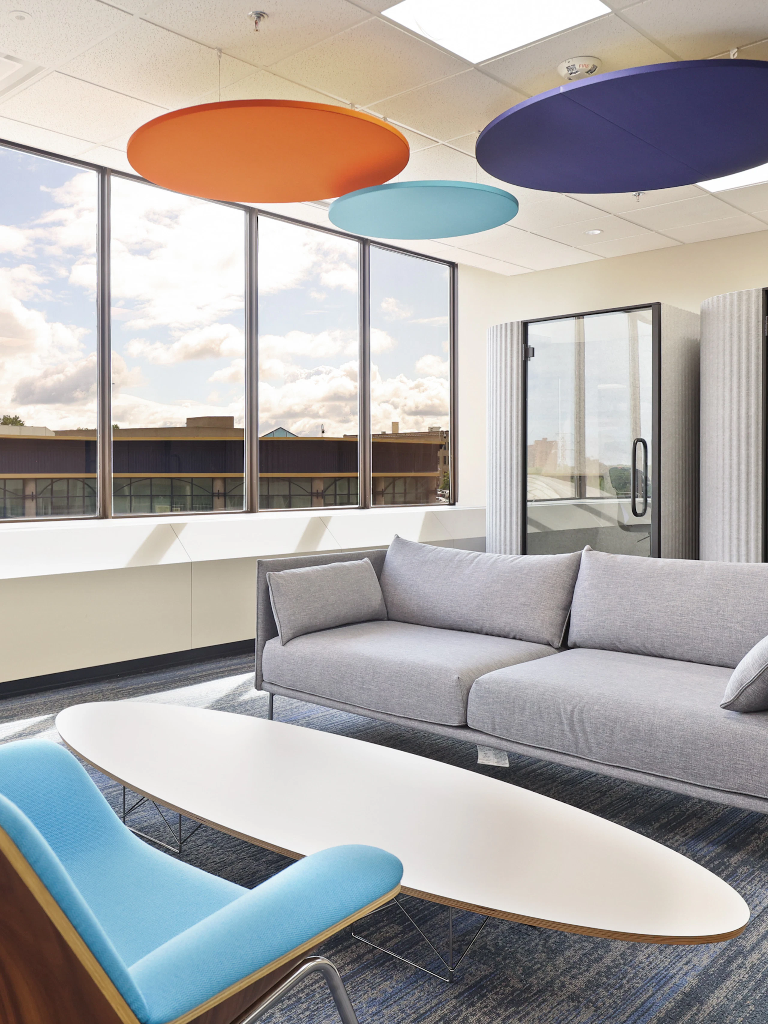 A group seating area at the Genesee County administration building furnished with a grey sofa, oval coffee table, and light blue lounge chair.
