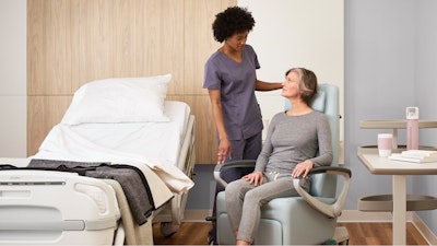 A nurse in a patient room having a conversation with a woman sitting in a Herman Miller Nemschoff Ava Recliner next to a hospital bed.