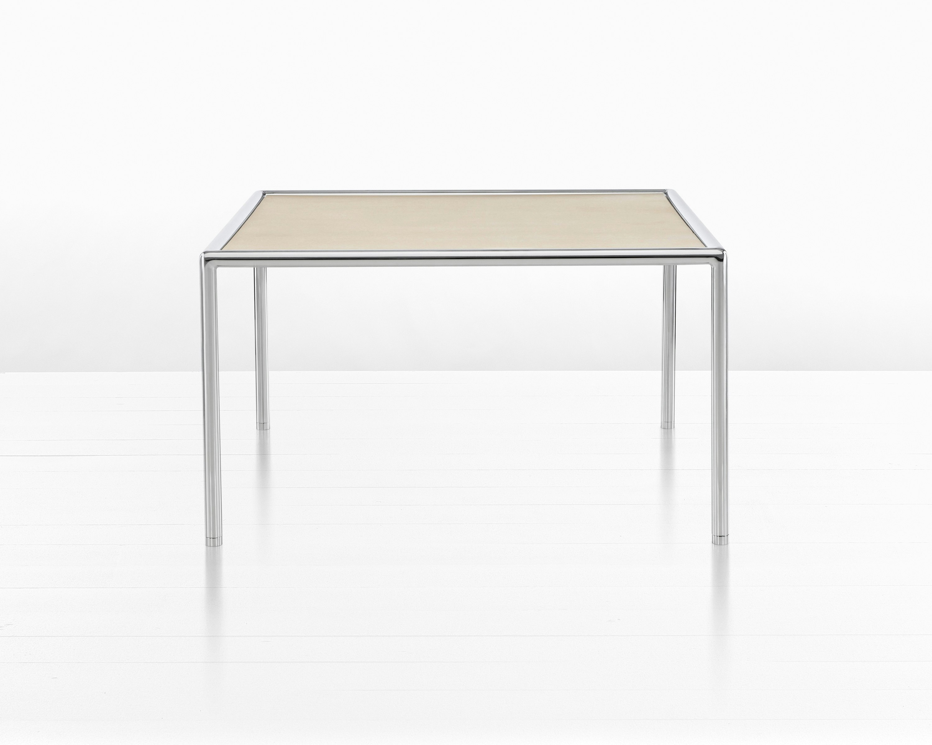 Partial view of a rectangular Full Round coffee table with a light wood top and tubular metal frame.