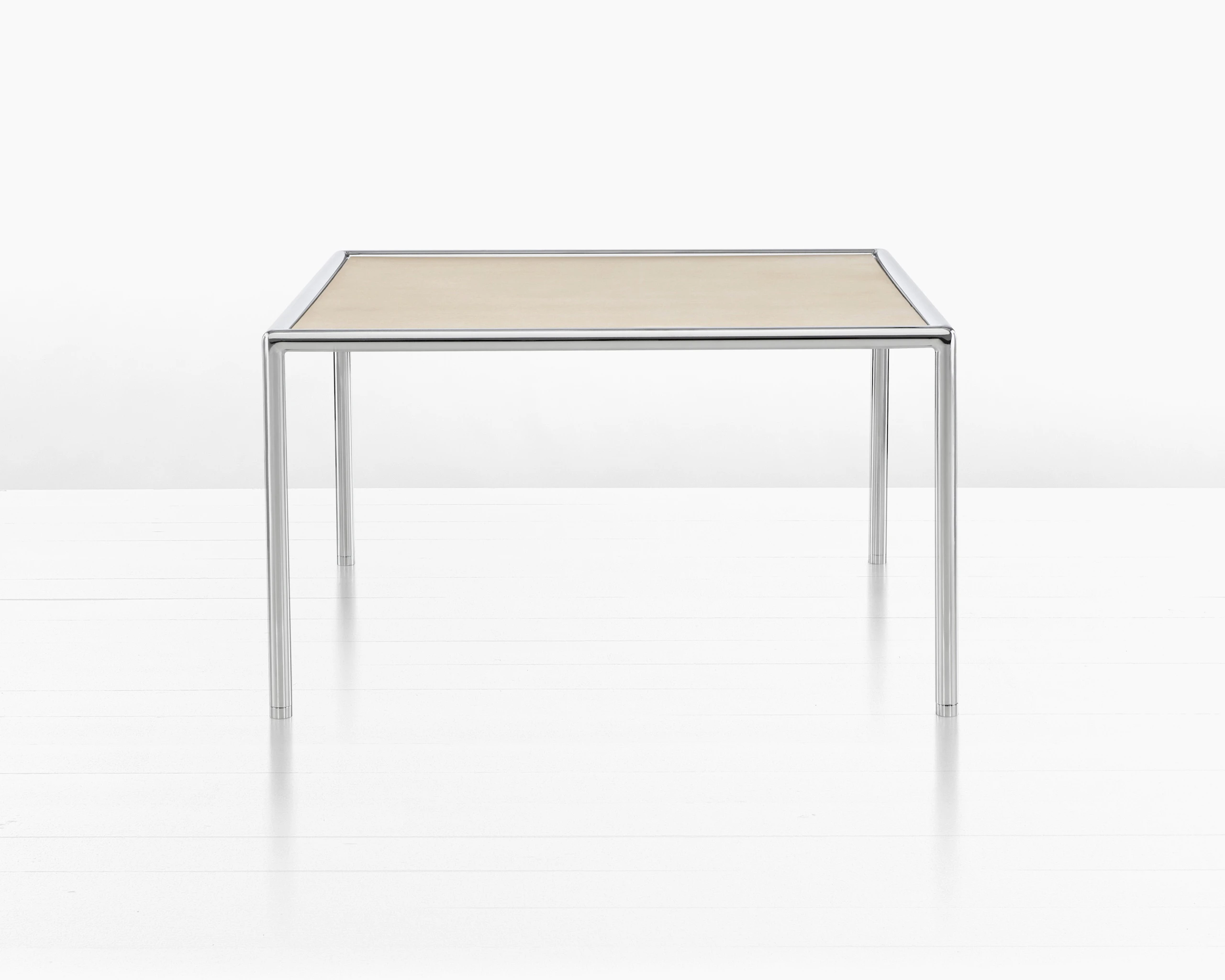 Partial view of a rectangular Full Round coffee table with a light wood top and tubular metal frame.