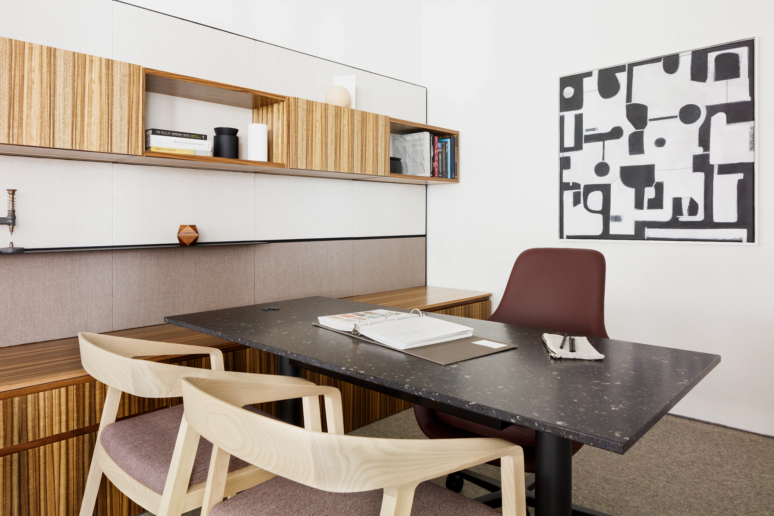Eye level view a Geiger One Casegoods private office in a high grain light and medium wood finish, with two light wood Full Twist chairs in the foreground, a height adjustable table in black marble with black legs, and reddish brown Saiba task chair.