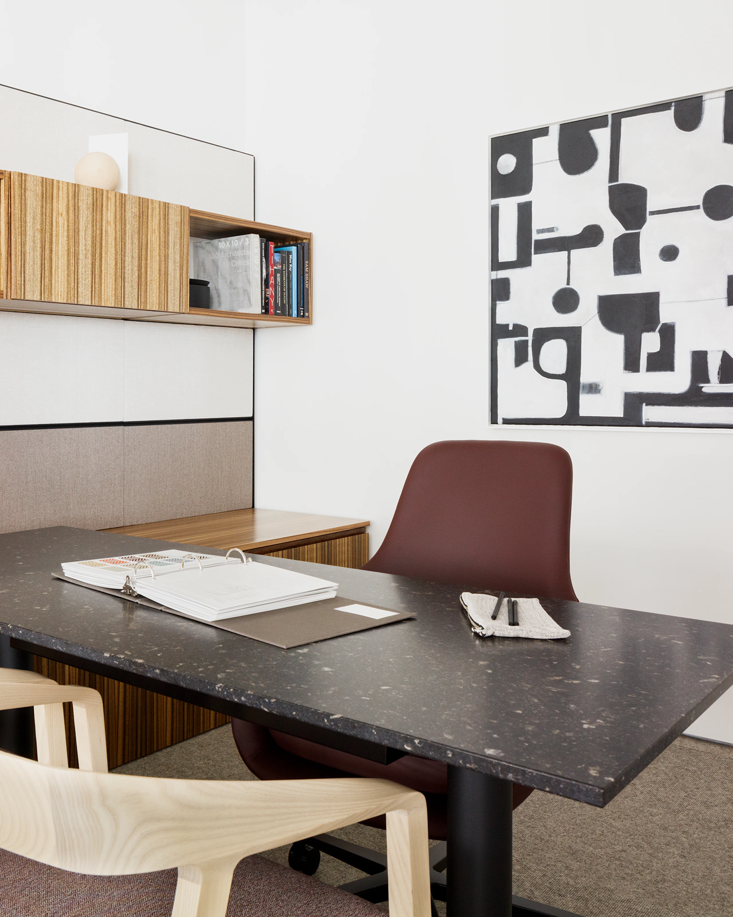 Eye level view a Geiger One Casegoods private office in a high grain light and medium wood finish, with two light wood Full Twist chairs in the foreground, a height adjustable table in black marble with black legs, and reddish brown Saiba task chair.
