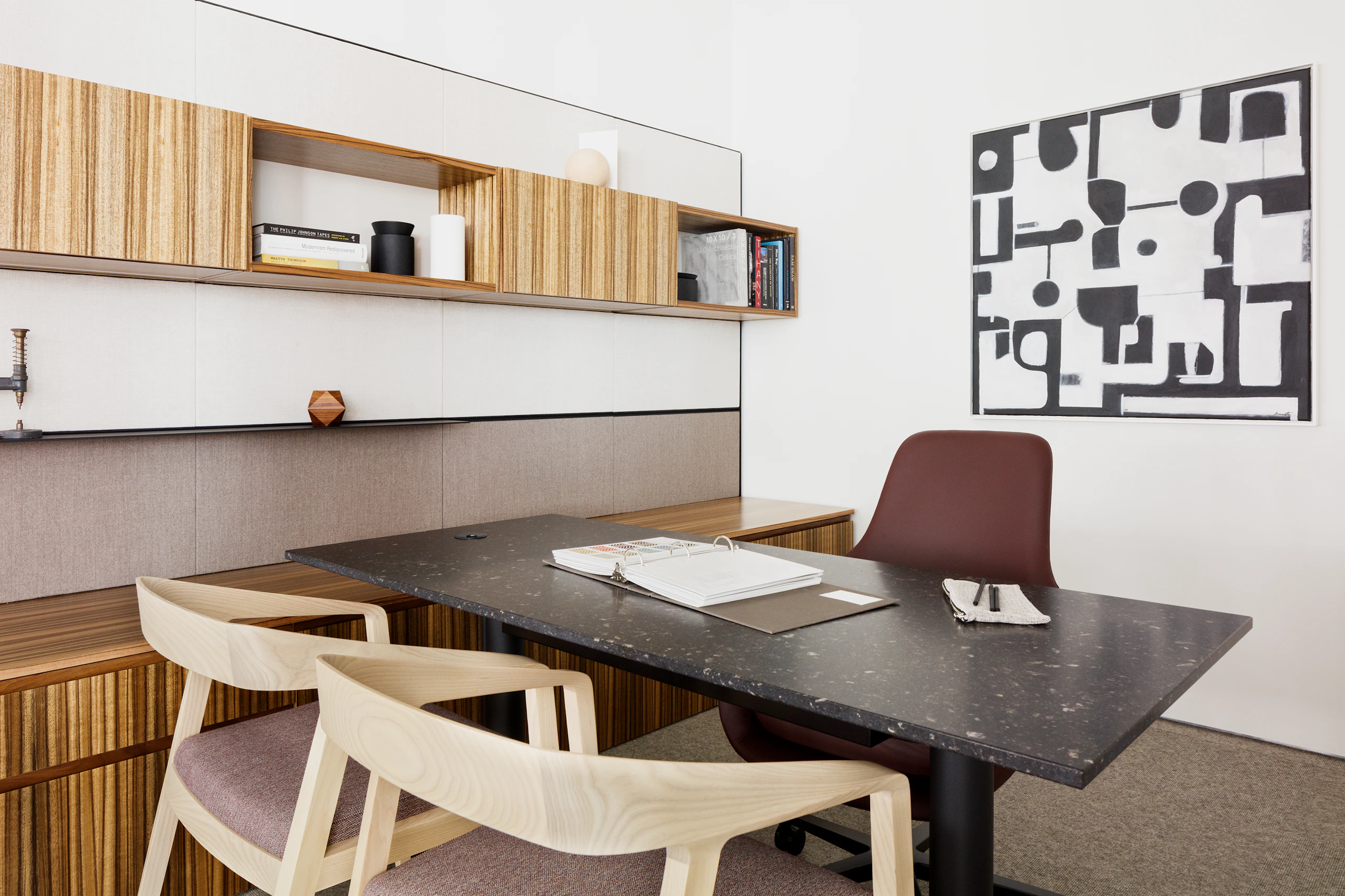 Eye level view a Geiger One Casegoods private office in a high grain light and medium wood finish, with two light wood Full Twist chairs in the foreground, a height adjustable table in black marble with black legs, and reddish brown Saiba task chair.