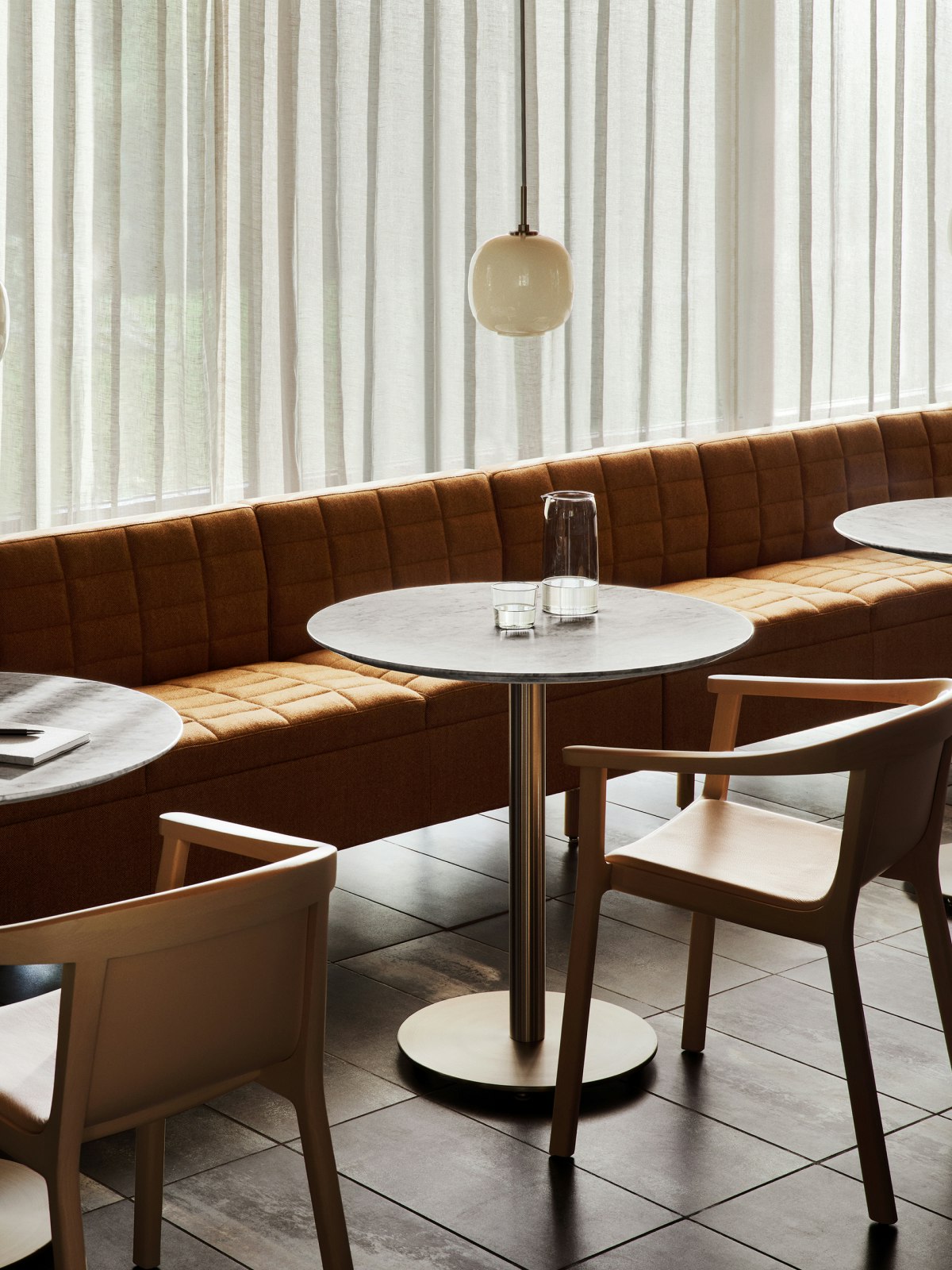 Tuxedo Classic Sofa in a cafe setting with Lijn Armchairs and cafe tables.