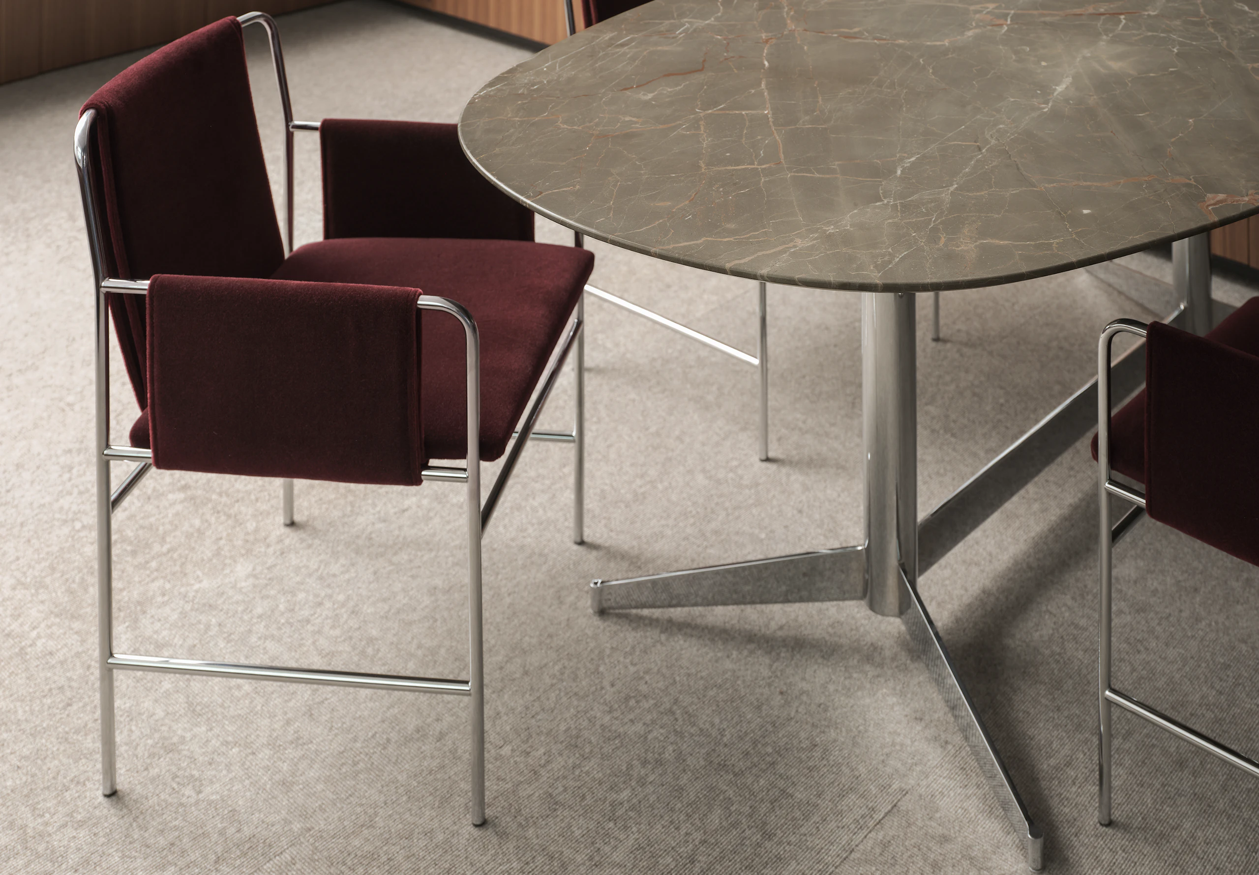 MP Table in Ombra di Caravaggio Marble with a chrome base with two Envelope Chairs upholstered with Knoll Velvet in Wine with chrome frames, viewed at an angle.