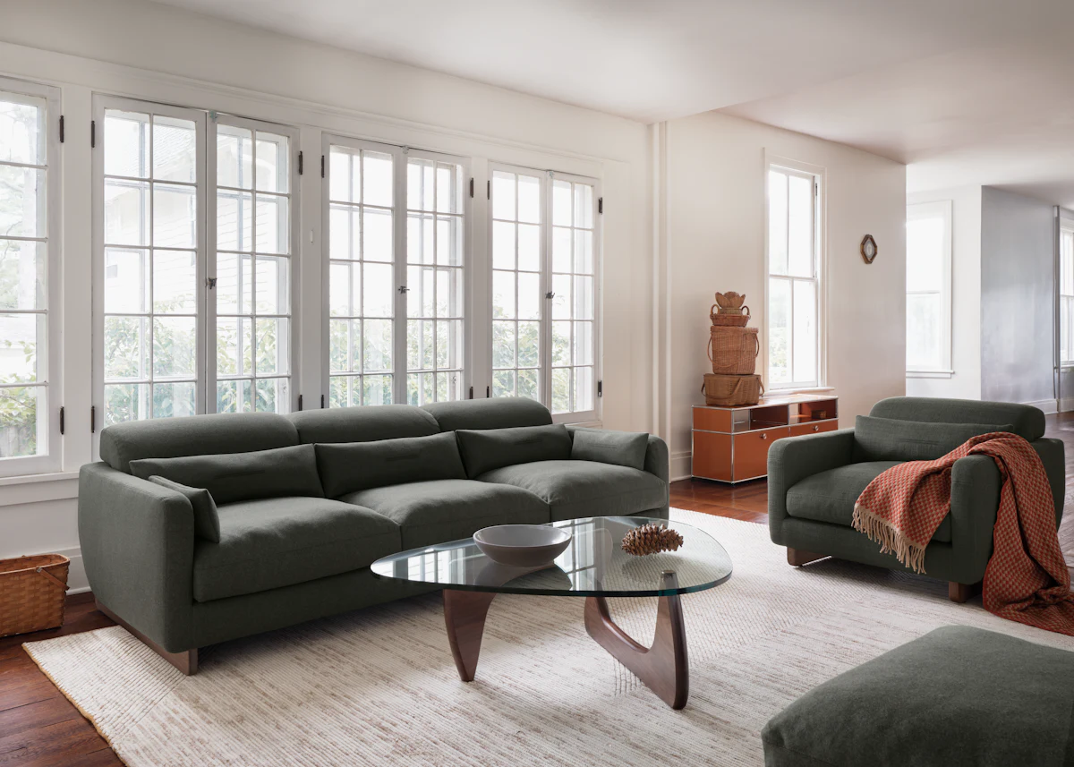 Open living room with sofa, chairs, coffee table and rug in neutral tones