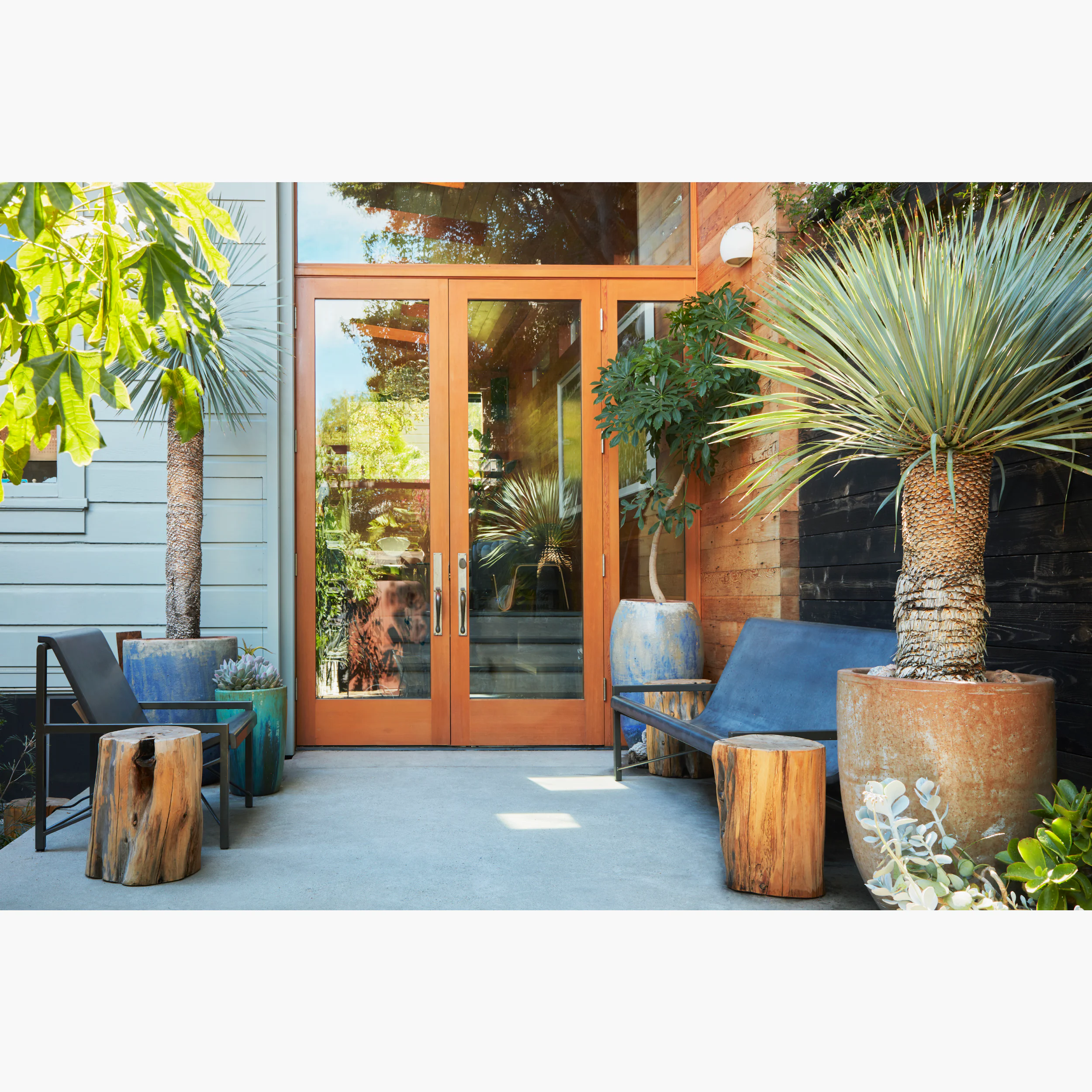 Outdoor patio scene with lounge furniture and potted plants.