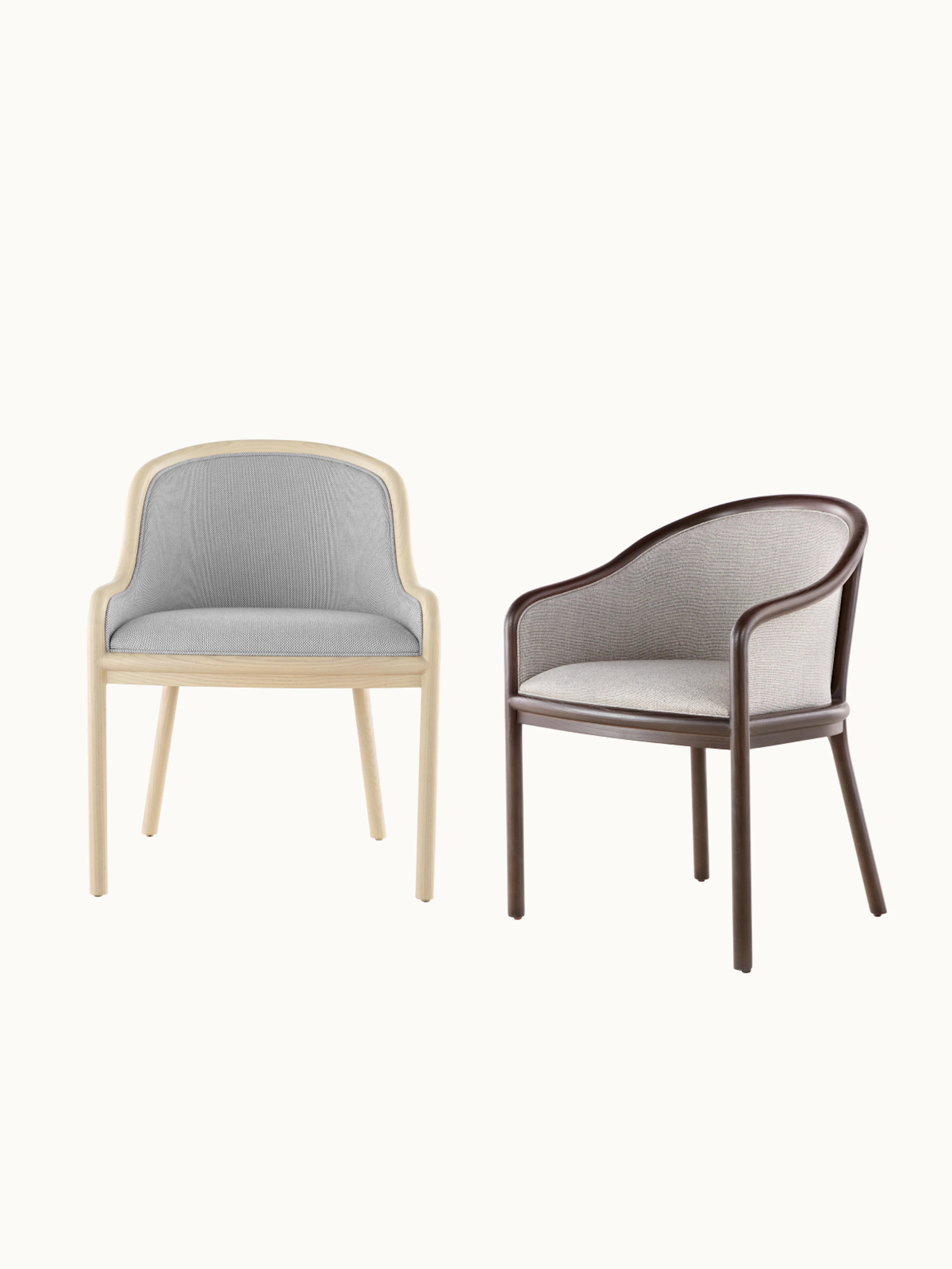 Two Landmark Chairs designed by Ward Bennett, one in a light wood finish with light grey upholstery front-facing, one in a dark wood finish with light beige upholstery shown at an angle, on a white sweep.