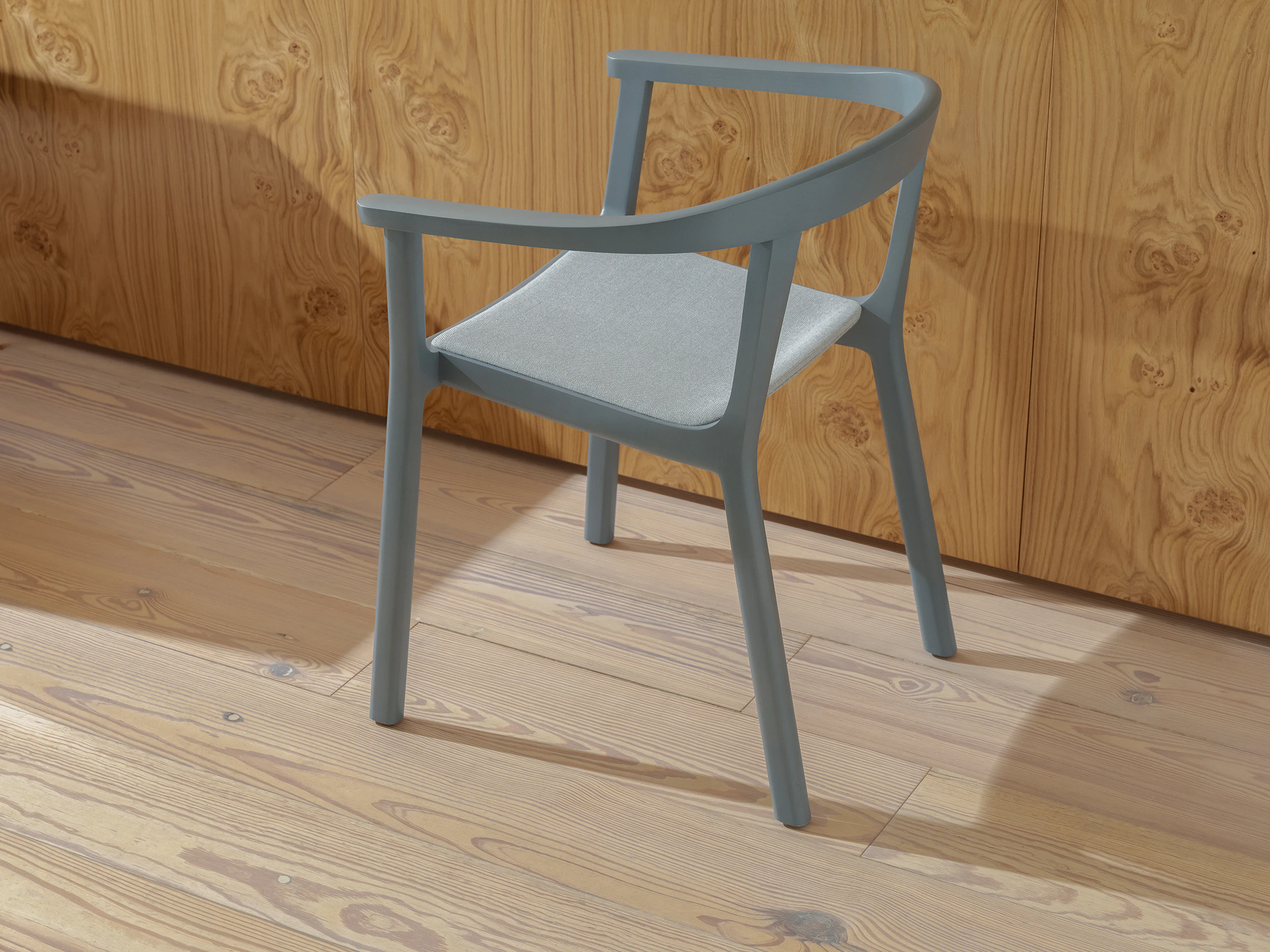 Lijn Armchair designed by Carole Baijings in Nordic Blue with the seat upholstered with Luce in Brine, viewed from behind at an angle against a veneer wall.