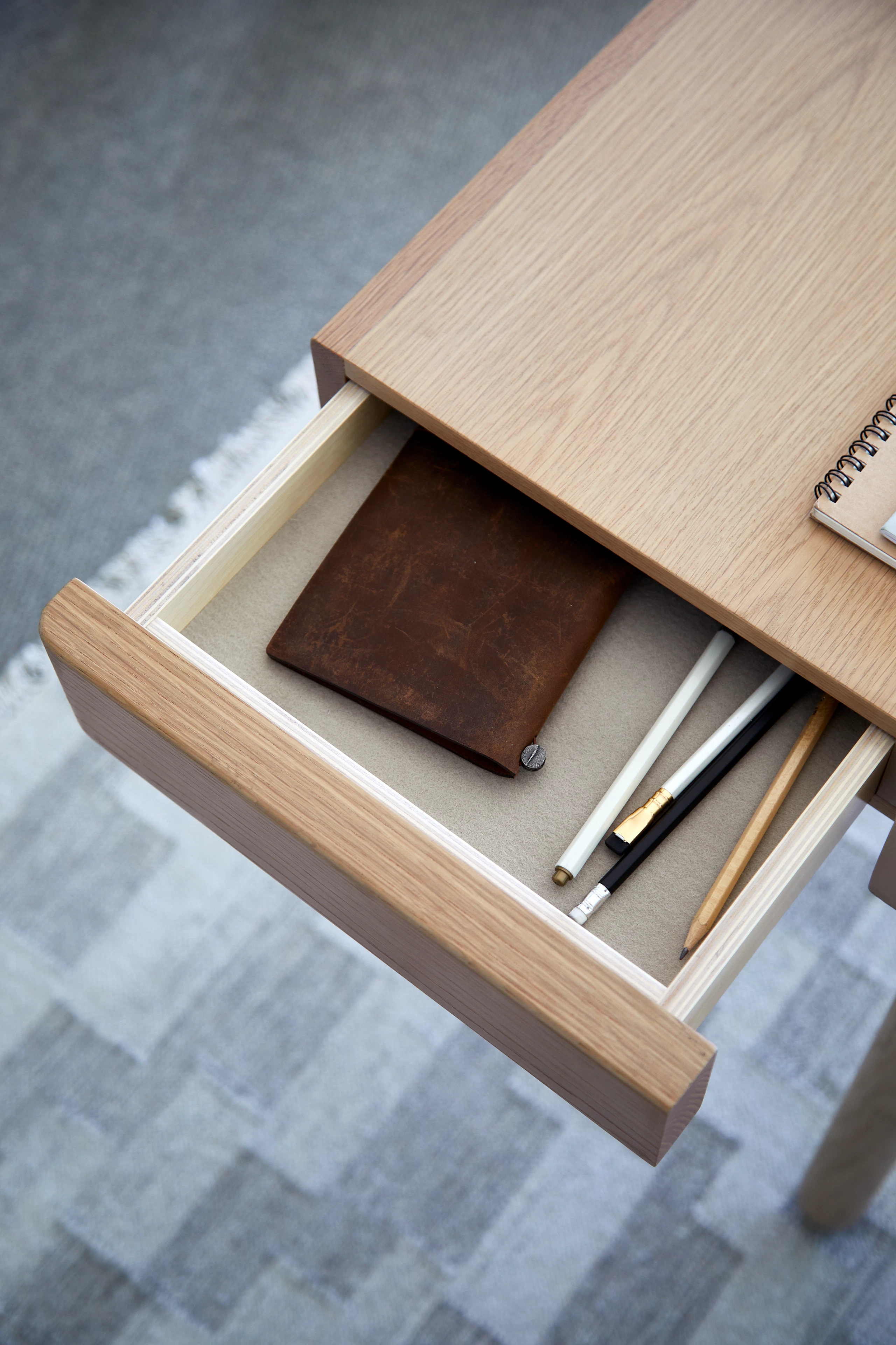 Detail of an open, felt-lined drawer on a New Canaan Height-Adjustable Desk by BassamFellows in Light Oak.