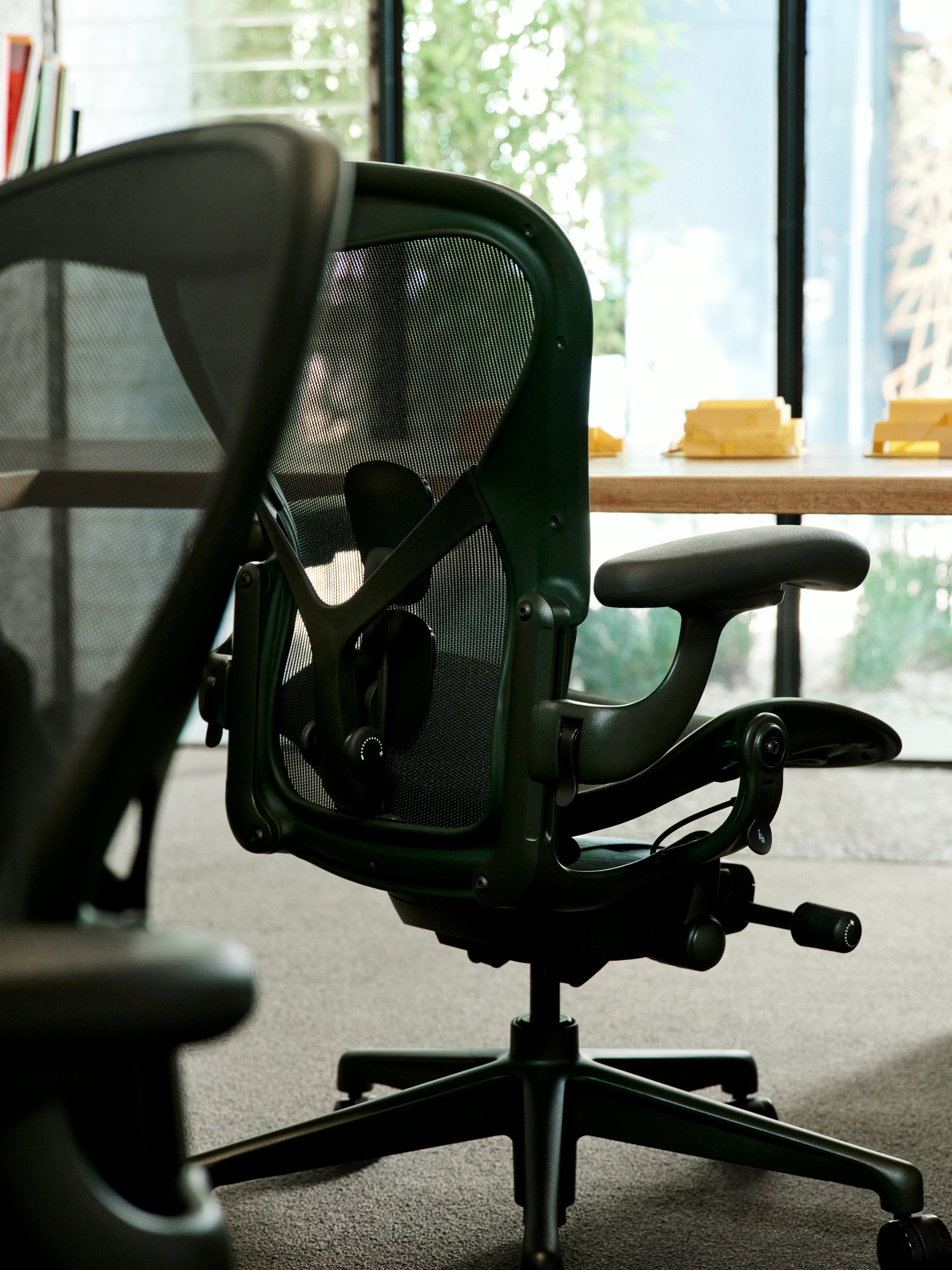 Close up of two dark green Aeron Chairs at a custom desk in an office.