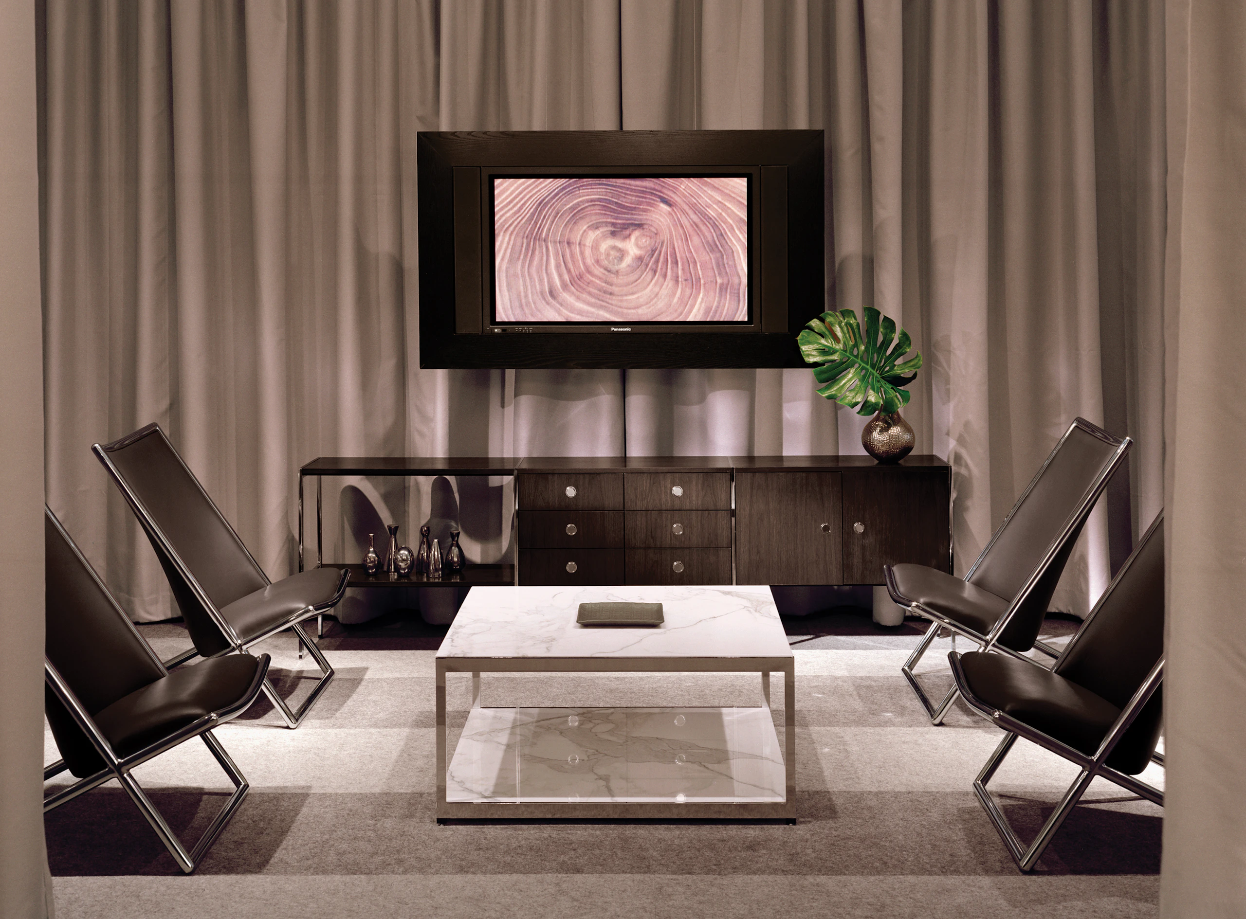 An interaction space furnished with a three-unit H Frame Storage credenza, a square H Frame Table, and four black leather Scissor Chairs.