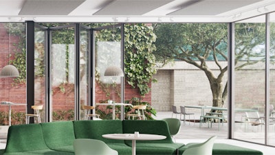 Salón con sofá verde y sillones claros, con vista al patio exterior a través de grandes puertas de vidrio. El patio cuenta con mesas, sillas y exuberante vegetación, incluido un árbol grande.