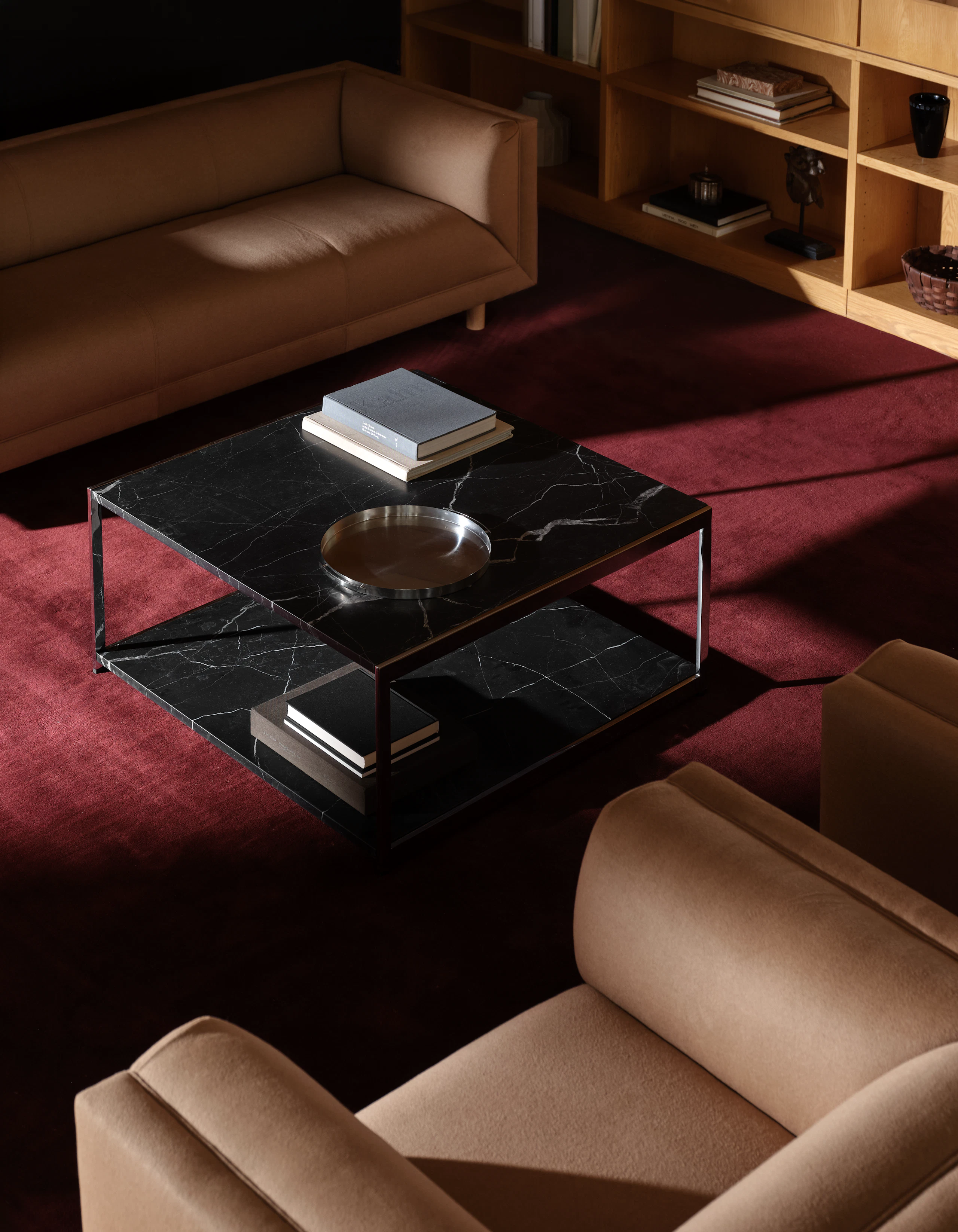 H Frame Coffee Table with a Nero Marquina Marble top and bottom and chrome frame, positioned between a Rolled Arm Sofa and two Rolled Arm Club Chairs, viewed from above at an angle on a burgundy rug.