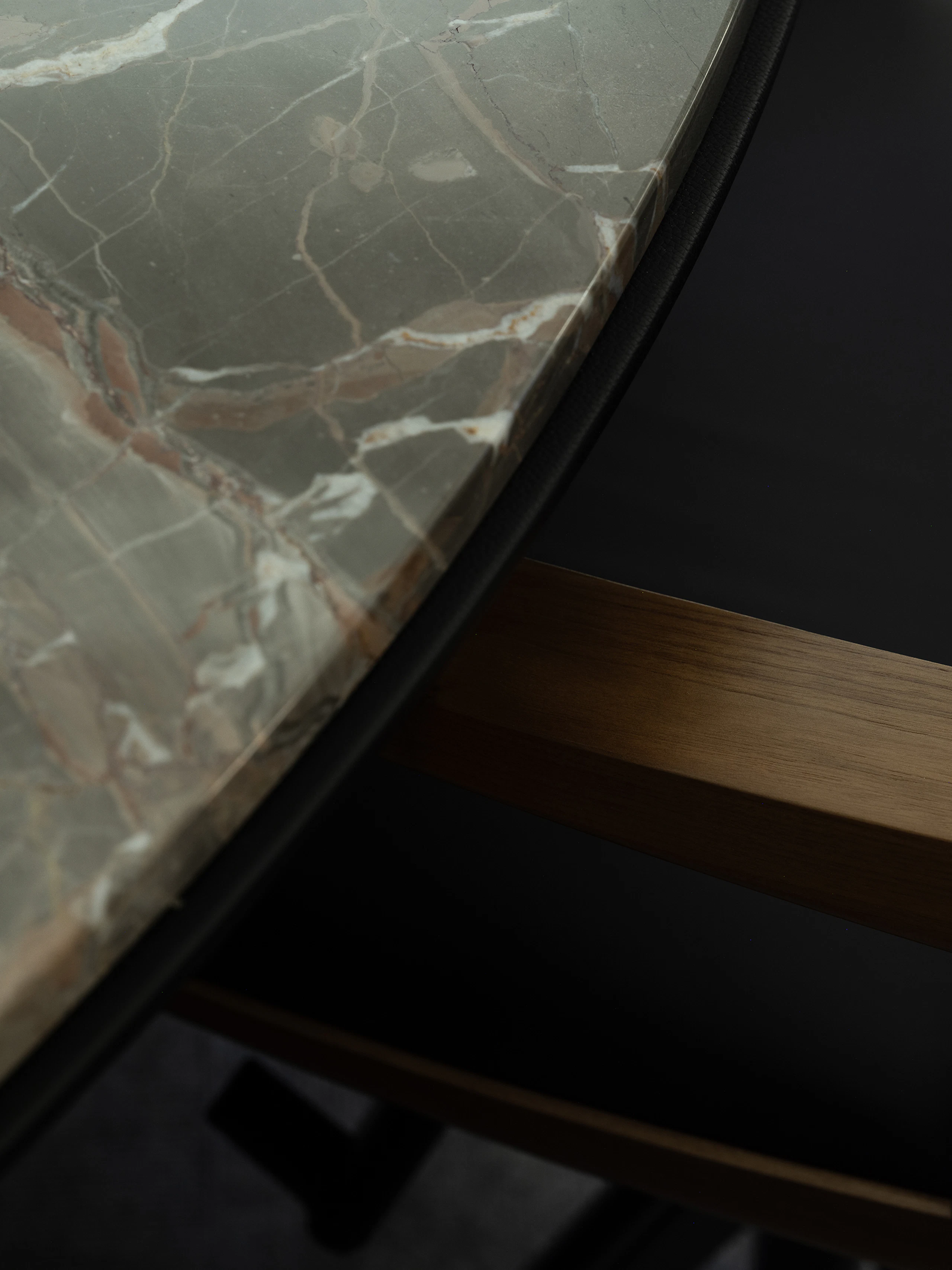 Detail view of a Clamshell Conference Chair in Walnut and black leather and a Highline Fifty Meeting Table with an Obra di Caravaggio Marble tabletop and black leather edge.
