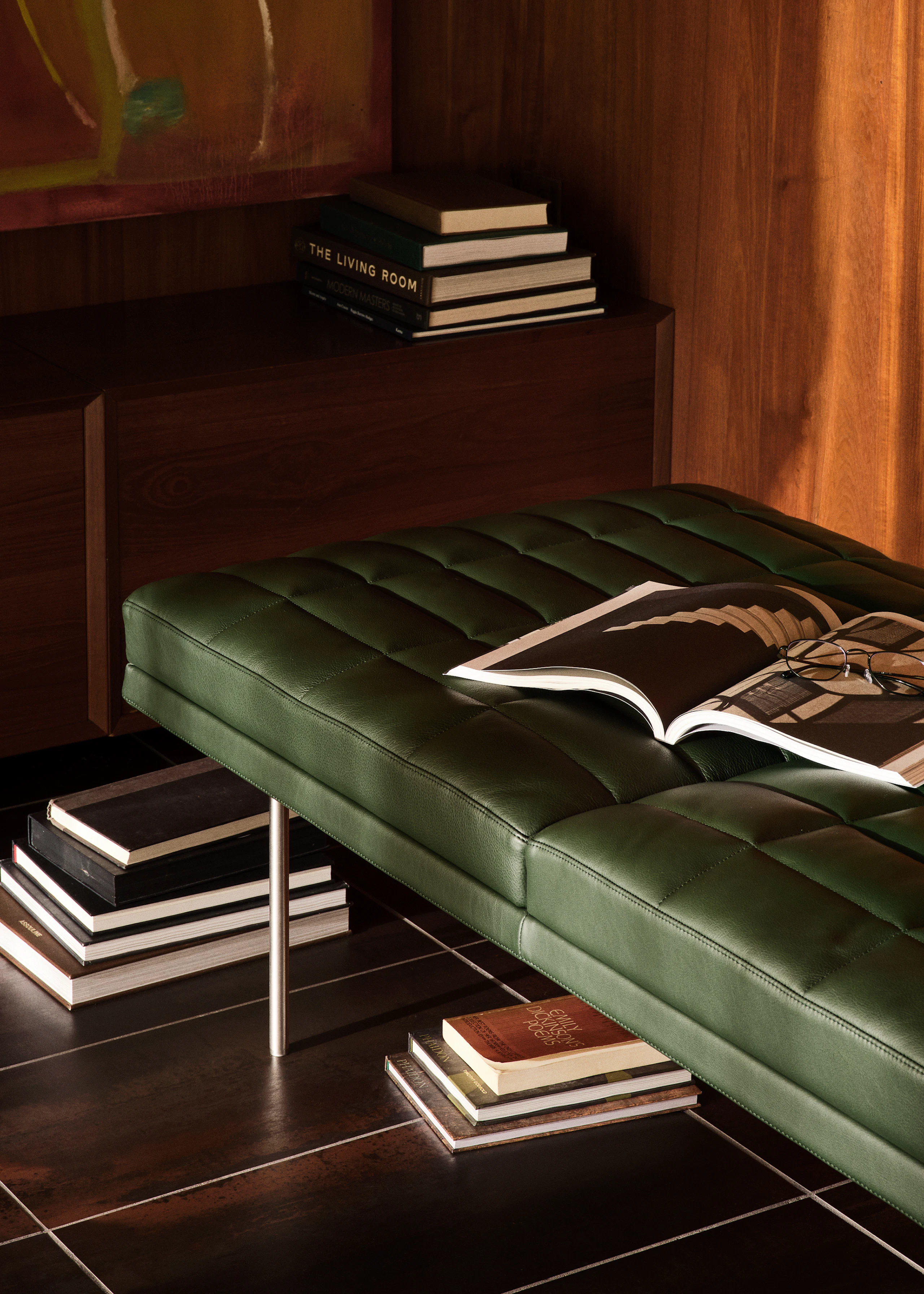 Tuxedo Component Bench designed by Bassam Fellows for Geiger in Prone Leather in Vine shown at an angle, styled with a variety of books.