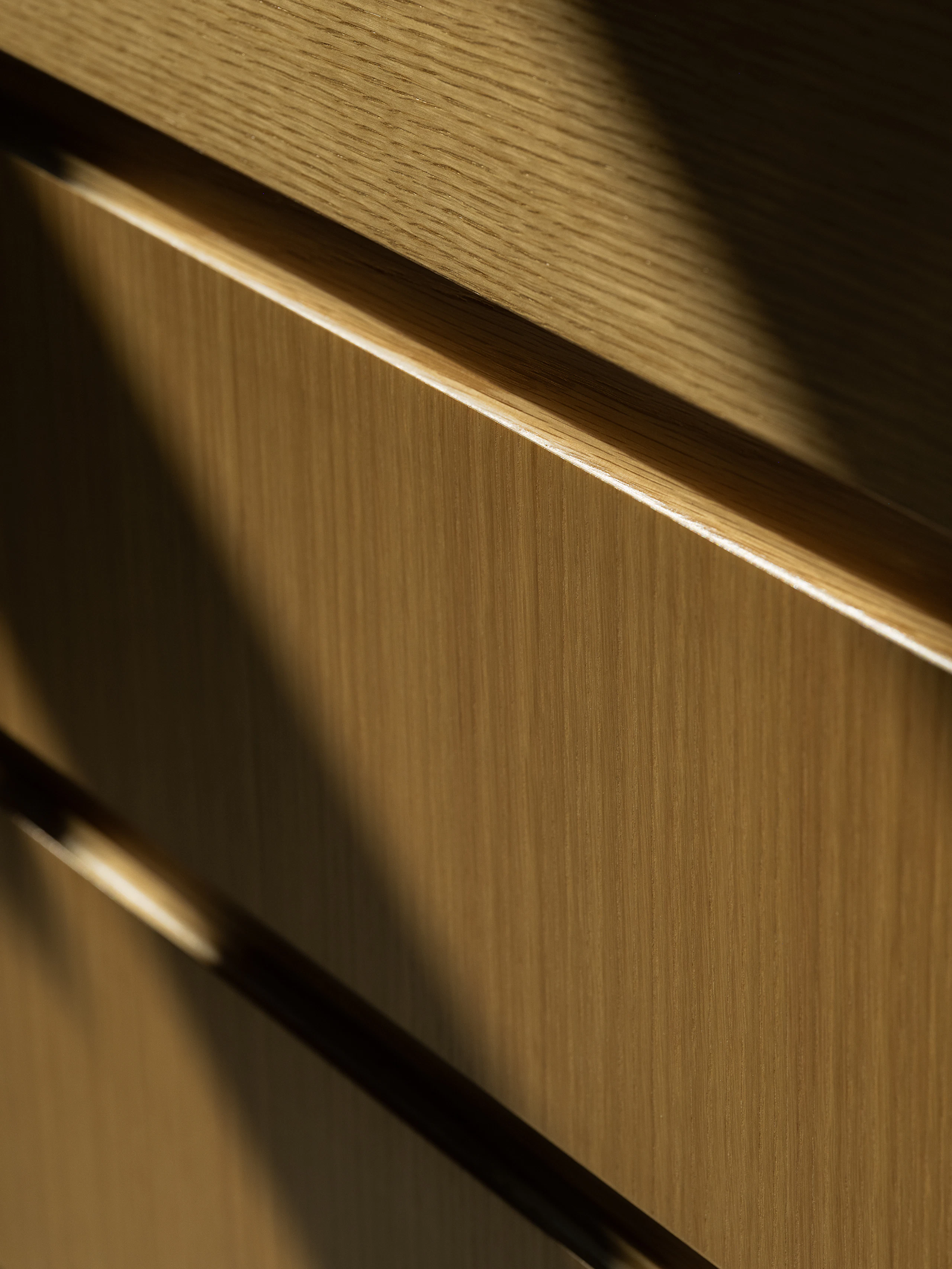 Detail shot of a custom storage solution in natural rift cut oak, viewed from an angle.