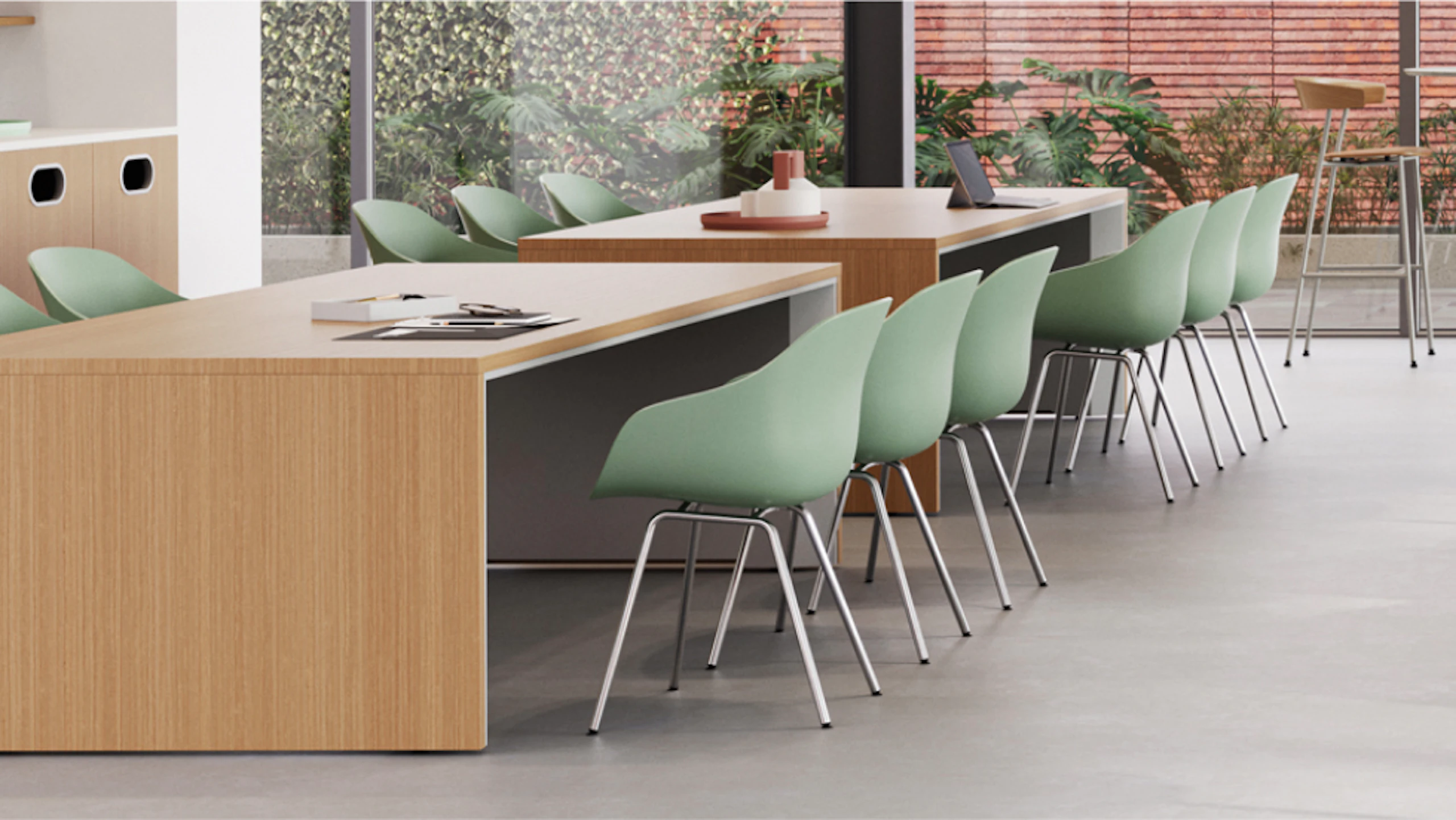 Modern space with two workstations, each featuring a desk, chair, and computer monitors. Shelving units with decor items are above the desks, and a glass partition separates the work areas.