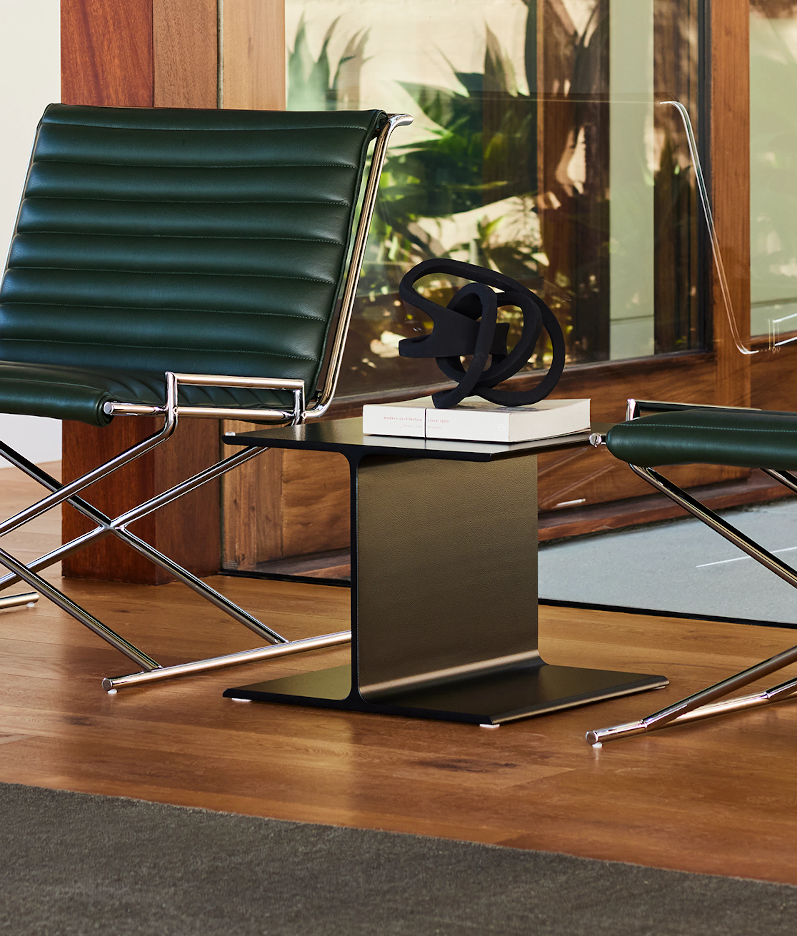 Two Sled Chairs with an I-Beam Side Table in an environmental setting.