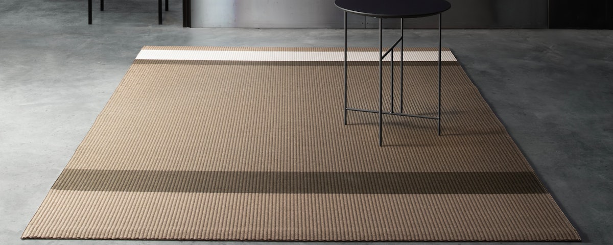 Panorama Paper Yarn Rug on a concrete studio floor with a cafe table