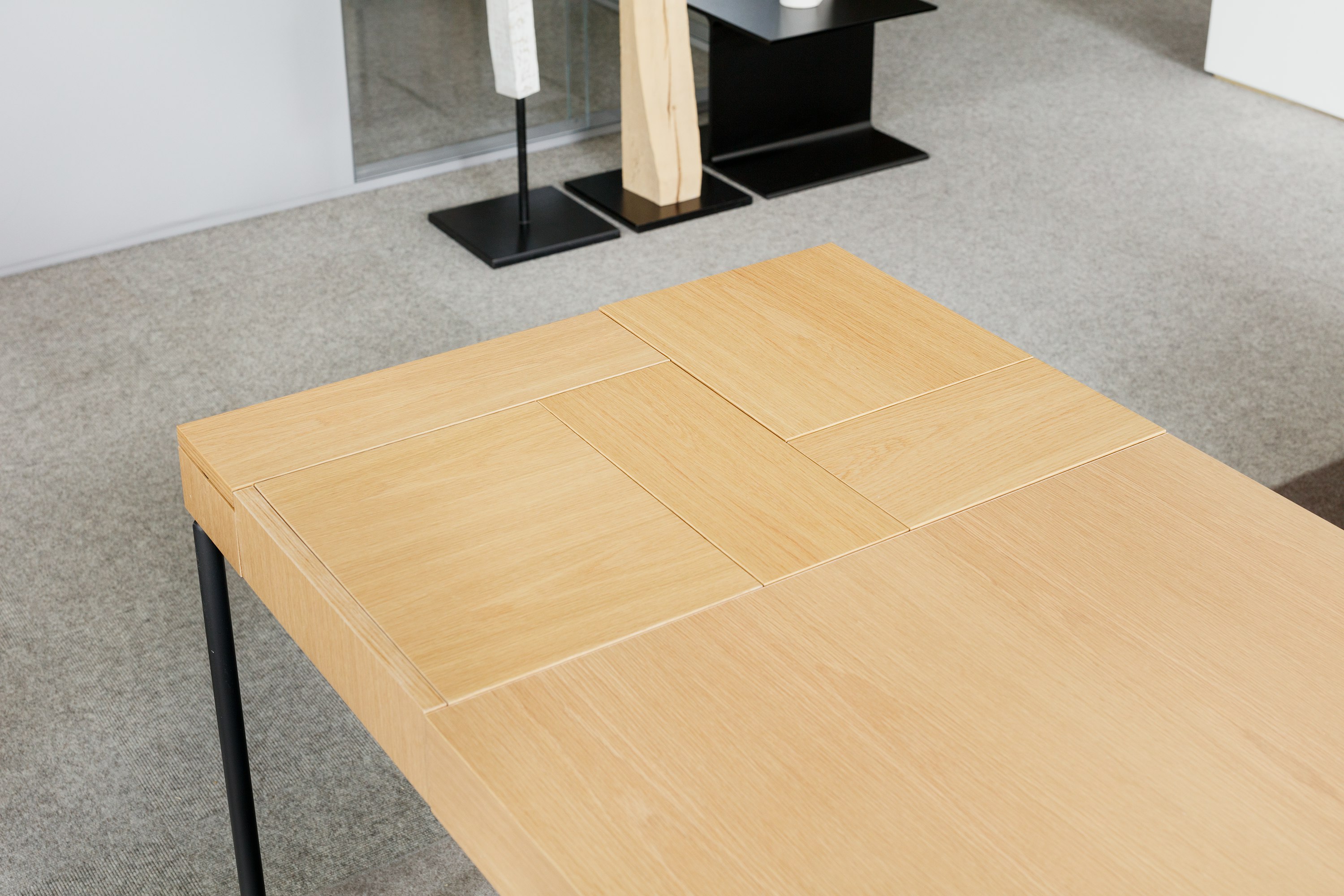 Close-up detailed view of the Domino Desk in light wood with black metal leg.