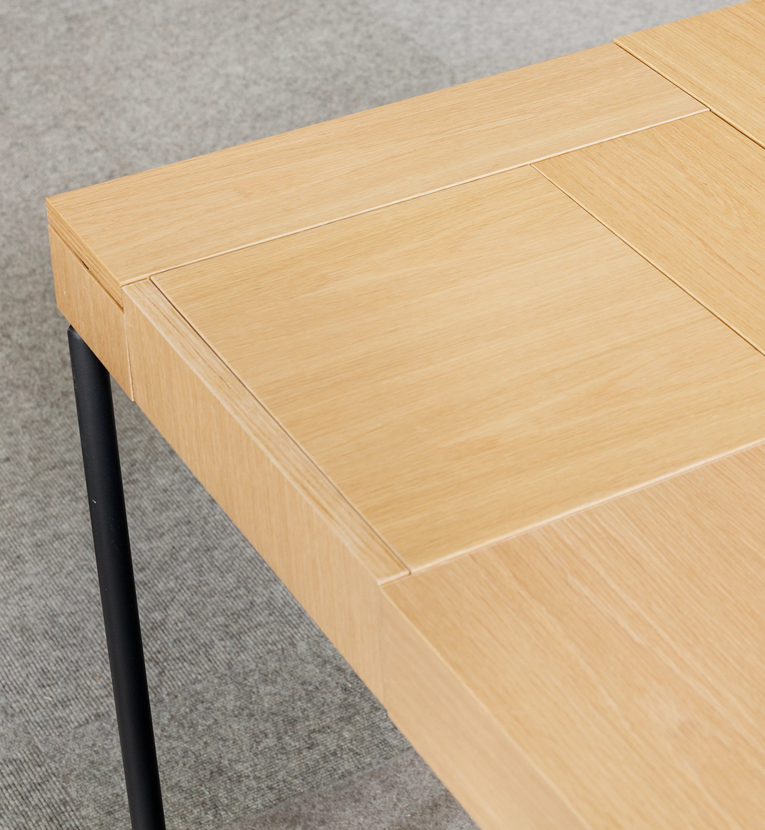 Close-up detailed view of the Domino Desk in light wood with black metal leg.